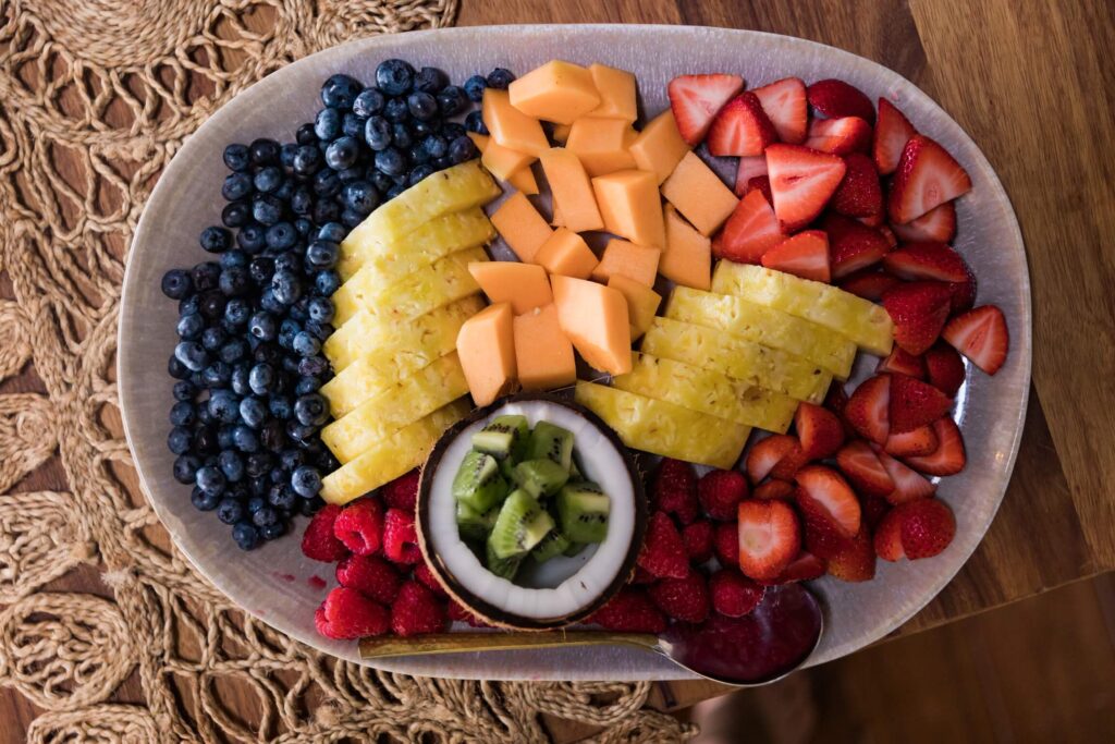 Platter of sliced pineapple, melon, strawberries, blueberries, raspberries and kiwi in a bowl.