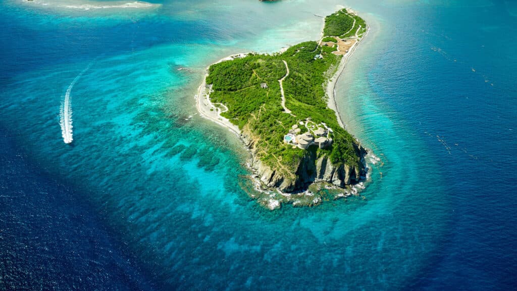 Aerial view of Buck Island surrounded by bright turquoise water with luxury villas perched on the cliffs.