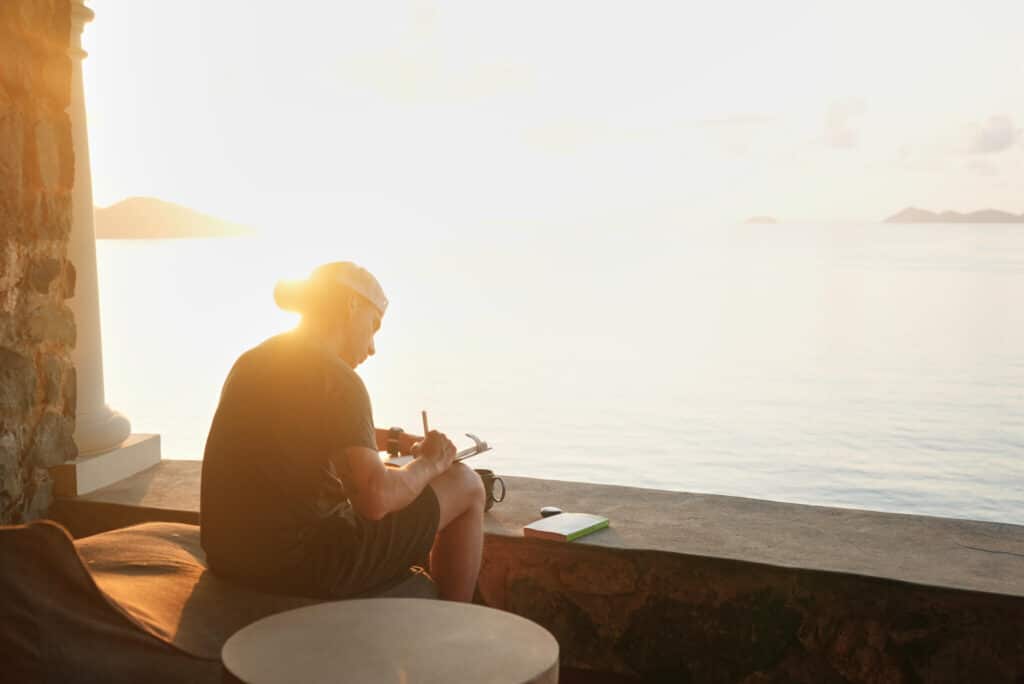 A guest journals quietly at sunrise overlooking calm ocean waters at The Aerial, BVI.