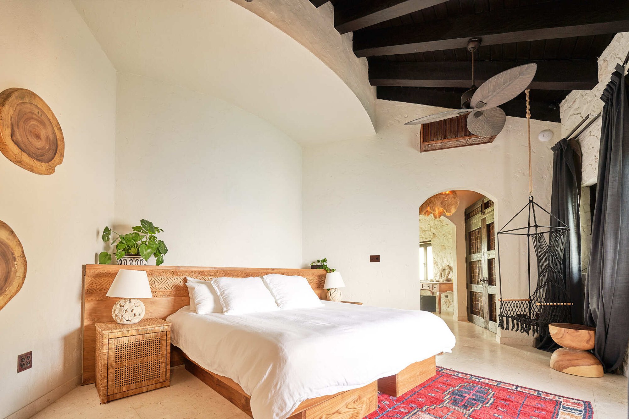 King bed with hanging chair and stone archway in the Presence room at The Aerial, BVI