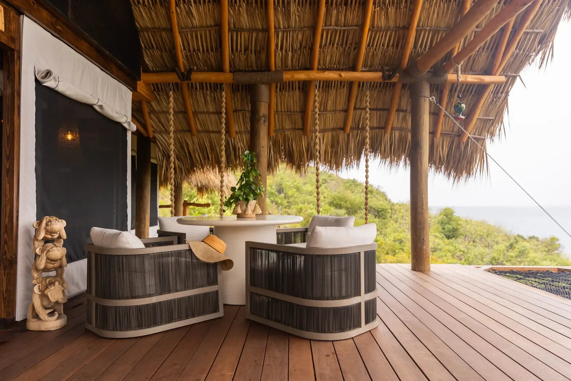 Covered deck with woven lounge chairs and round table.