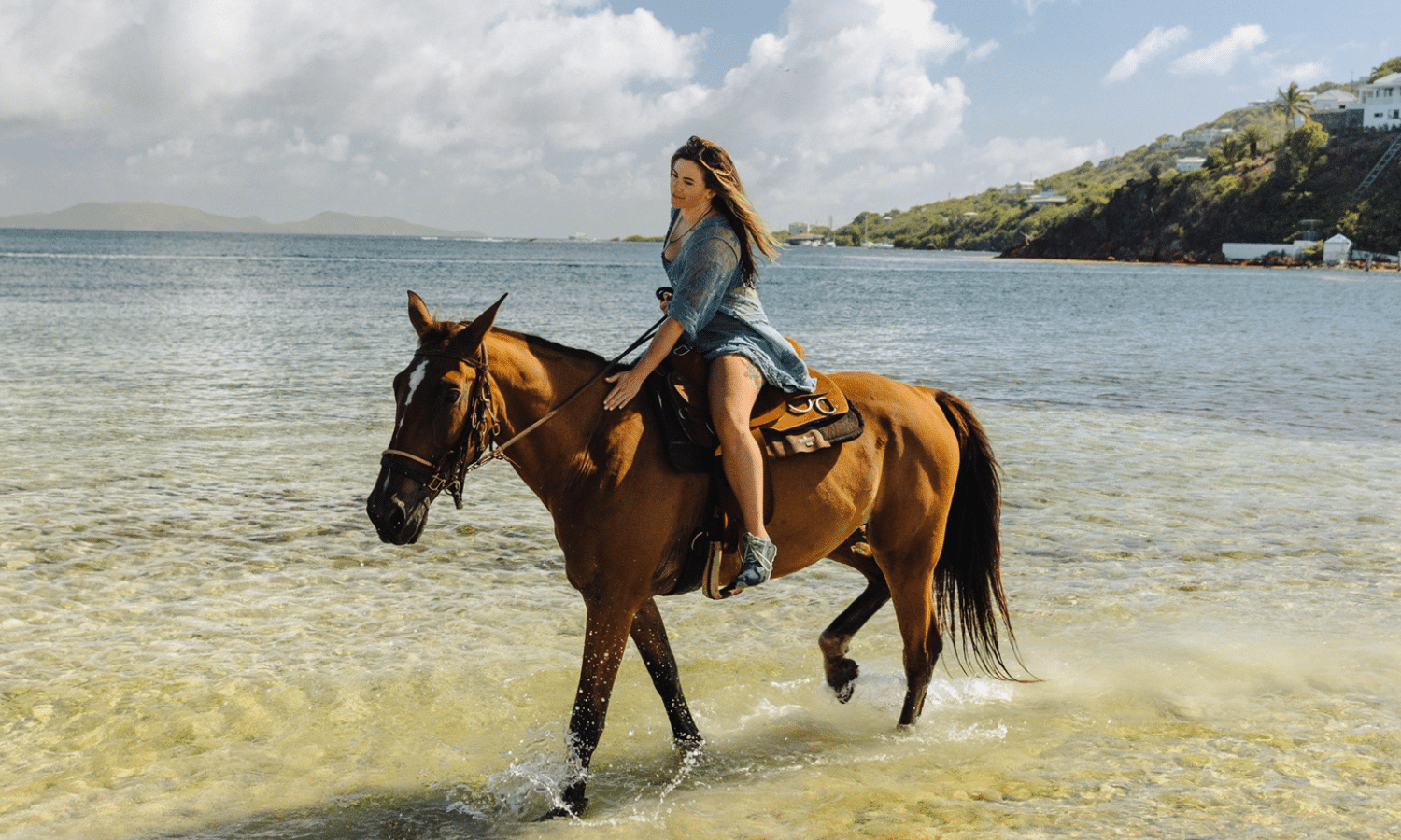 Woman horseback riding through shallow water on The Aerial BVI's private beach