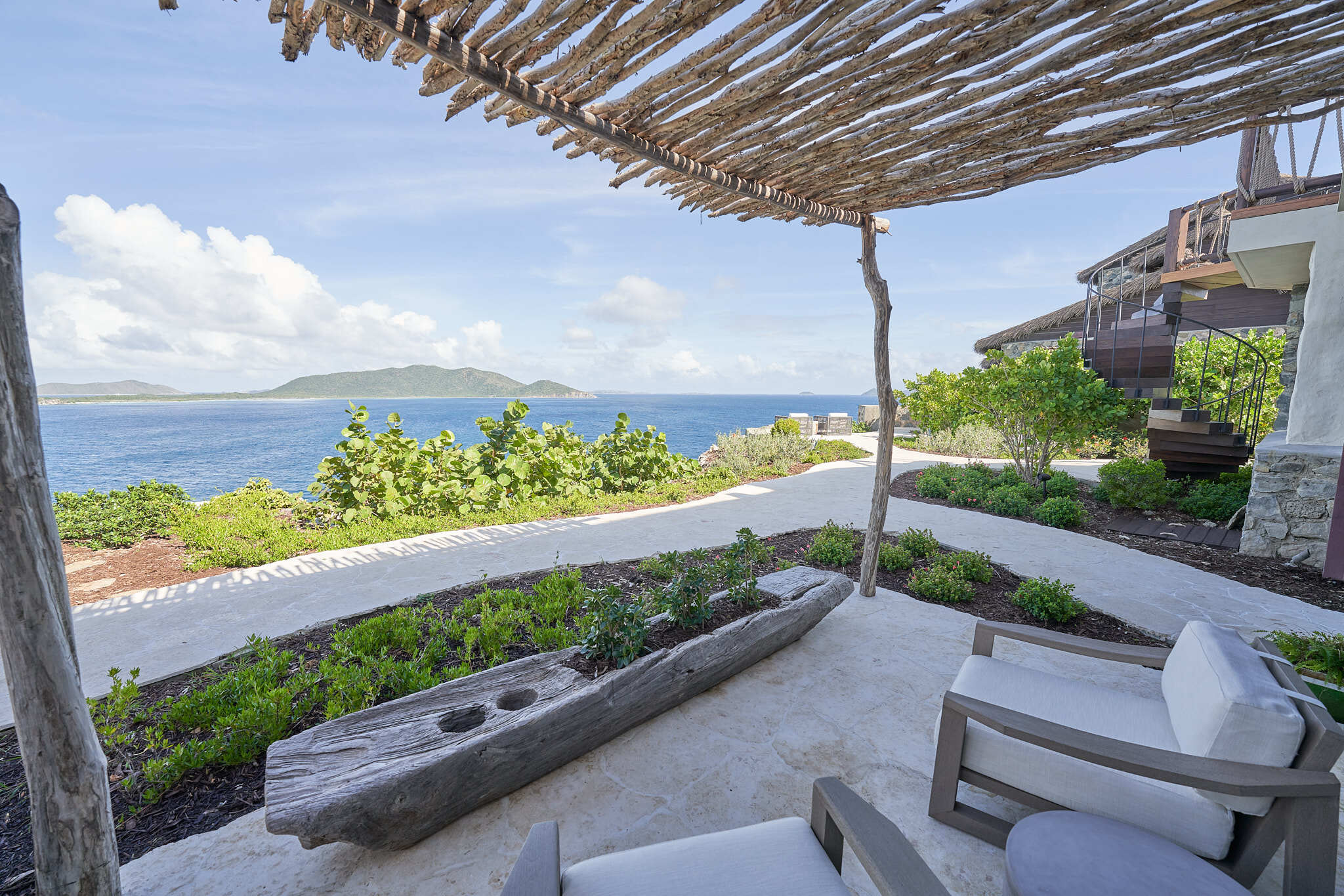 Garden pathway with ocean view under a thatched pergola.