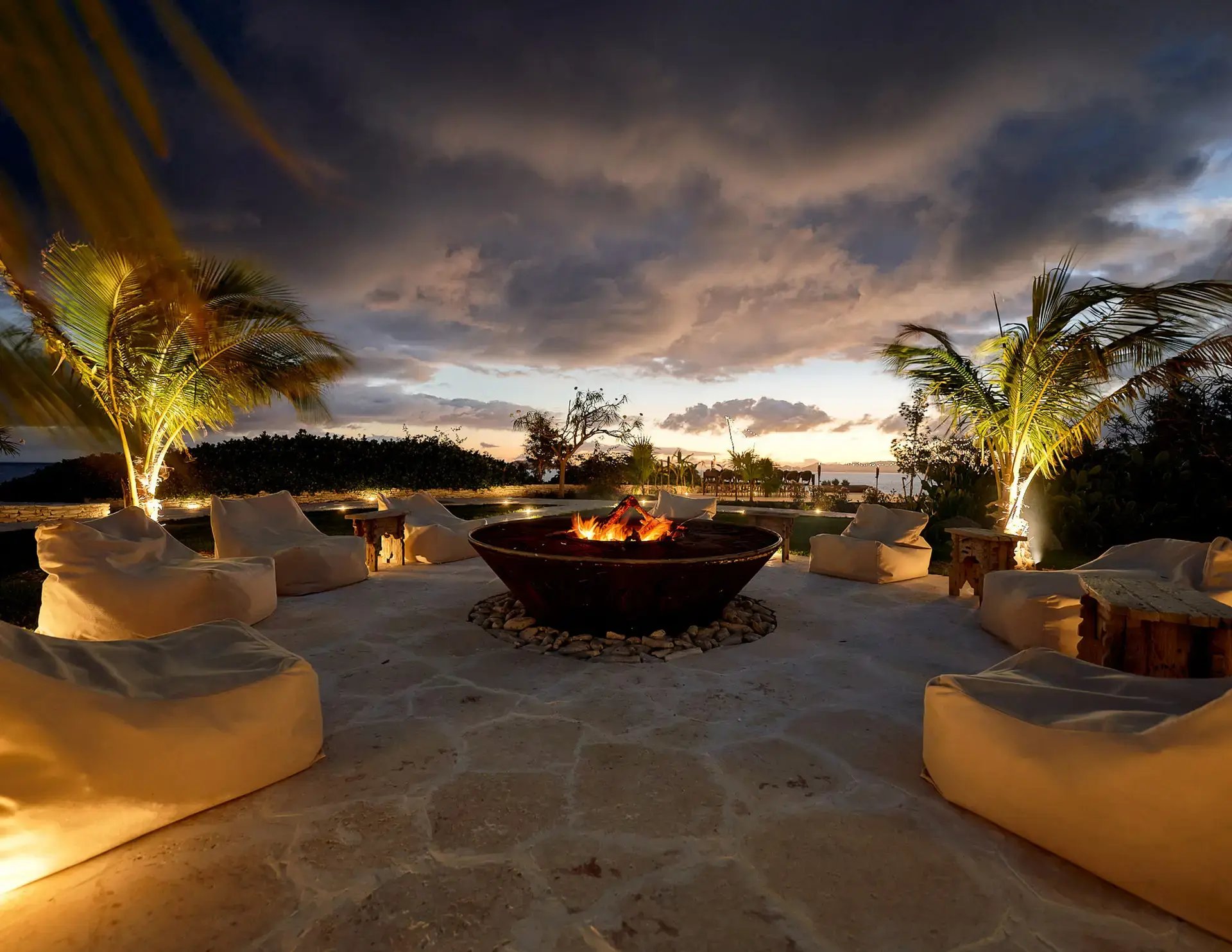 Fire pit lounge area at dusk with palm trees at The Aerial, BVI