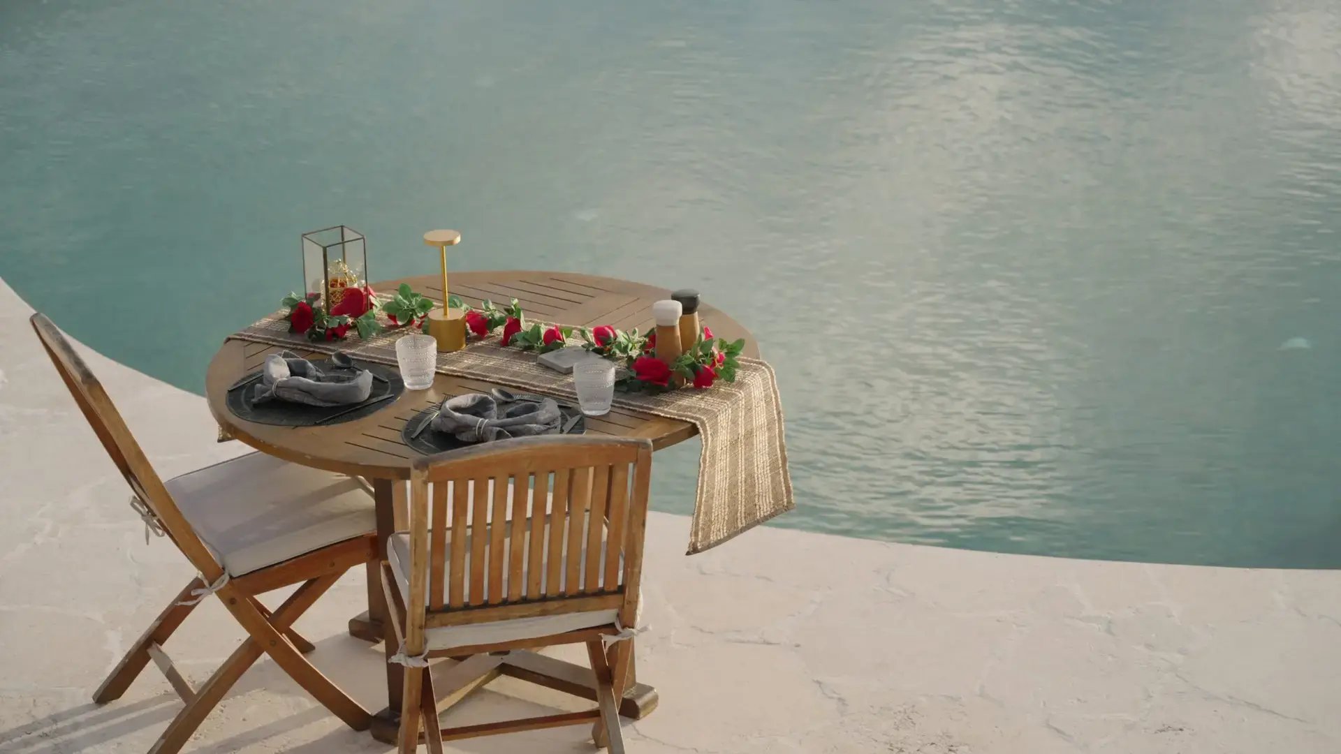 Table set for two beside the pool overlooking the ocean at The Aerial BVI