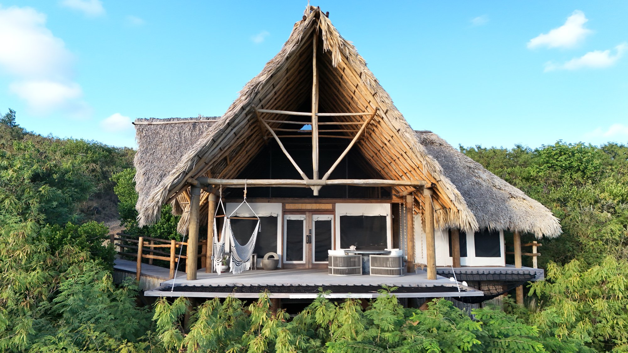 Thatched-roof villa exterior surrounded by tropical greenery.