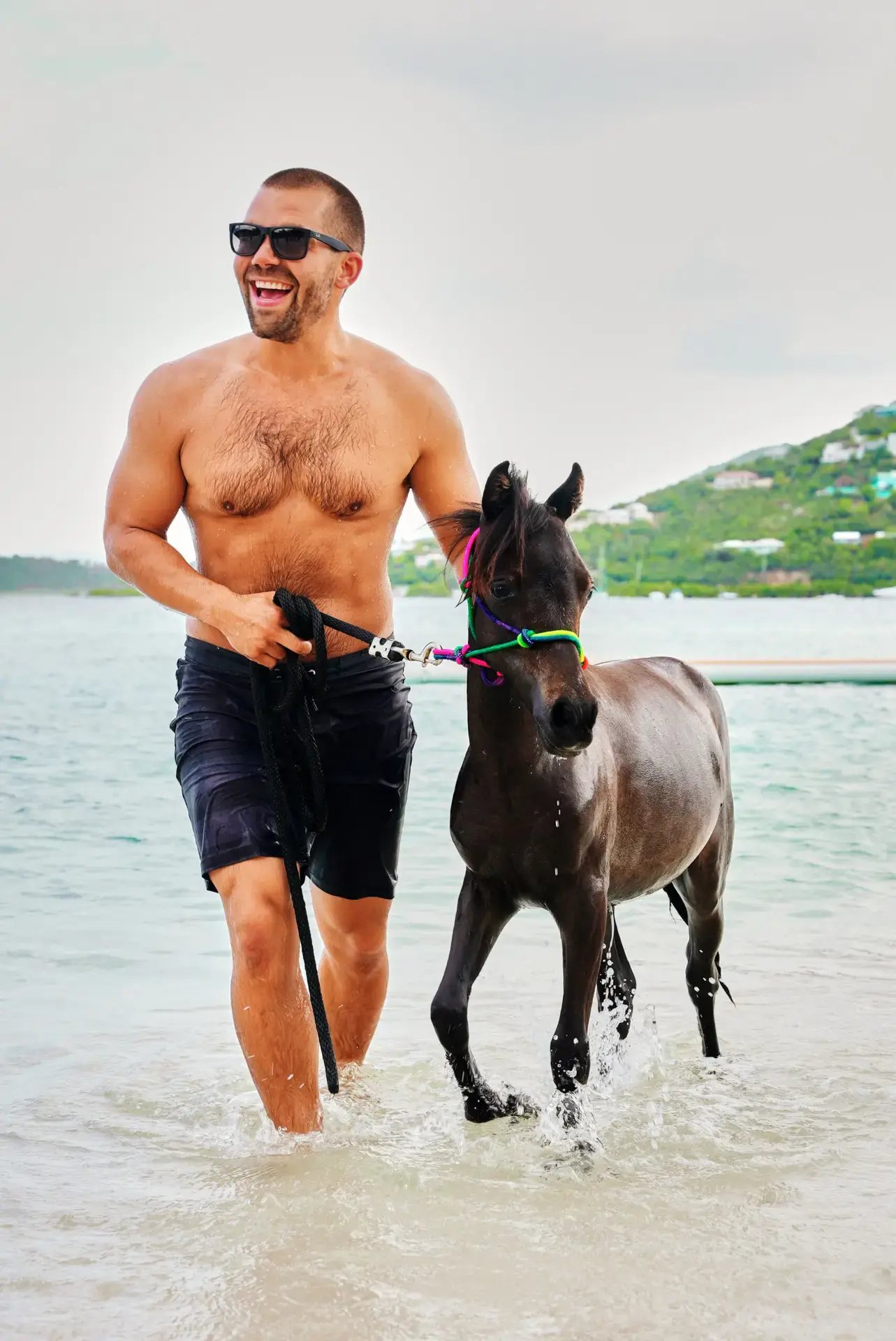 Man running through shallow water with a rescue horse at Redemption Ranch, The Aerial BVI