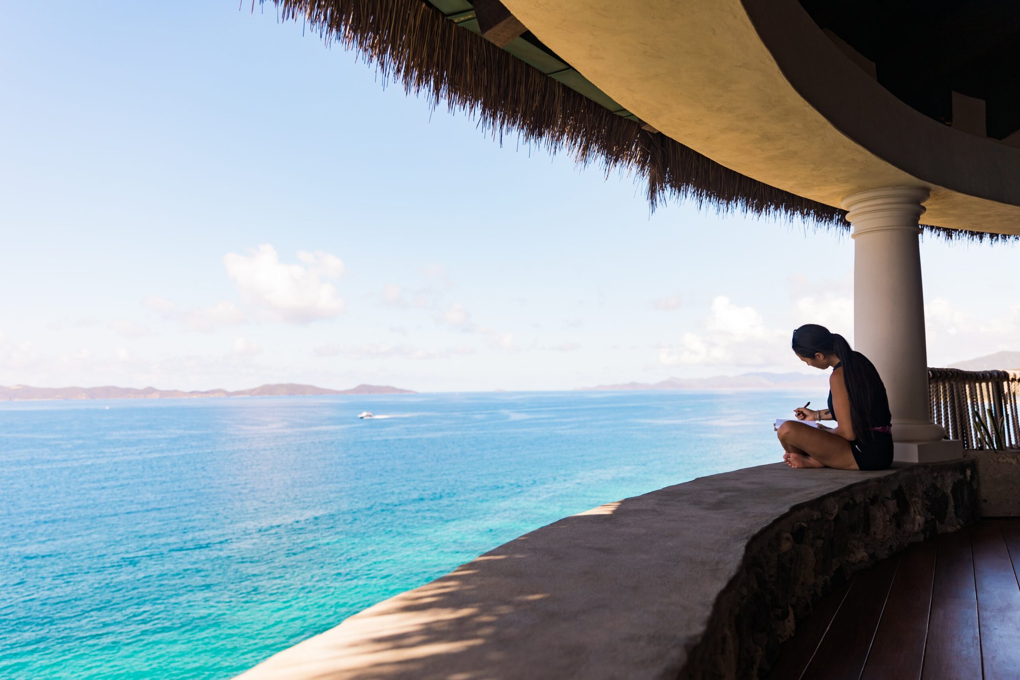 Guest relaxing under a thatched pavilion overlooking the ocean at The Aerial, BVI.