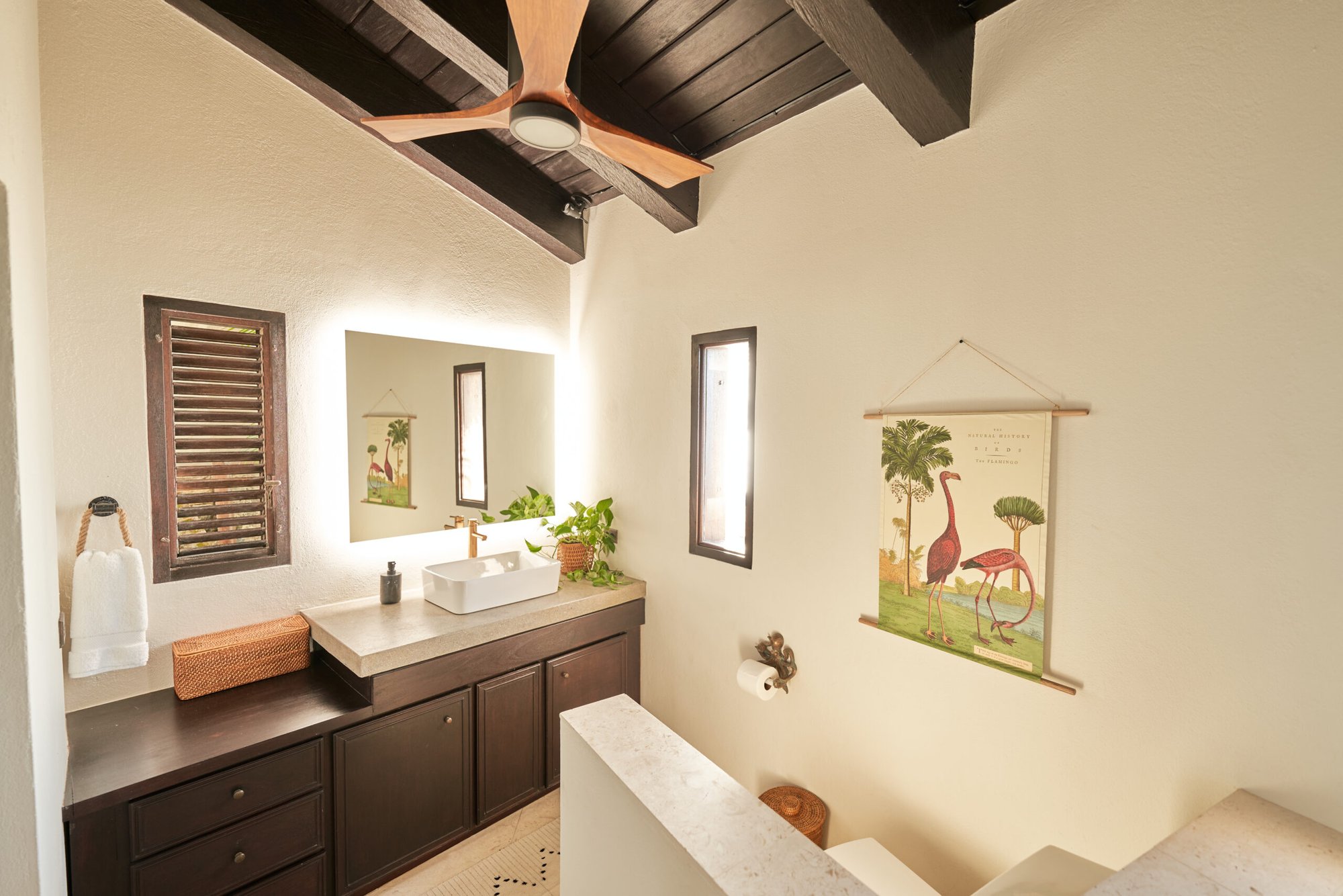 Bathroom vanity with backlit mirror and flamingo wall art.