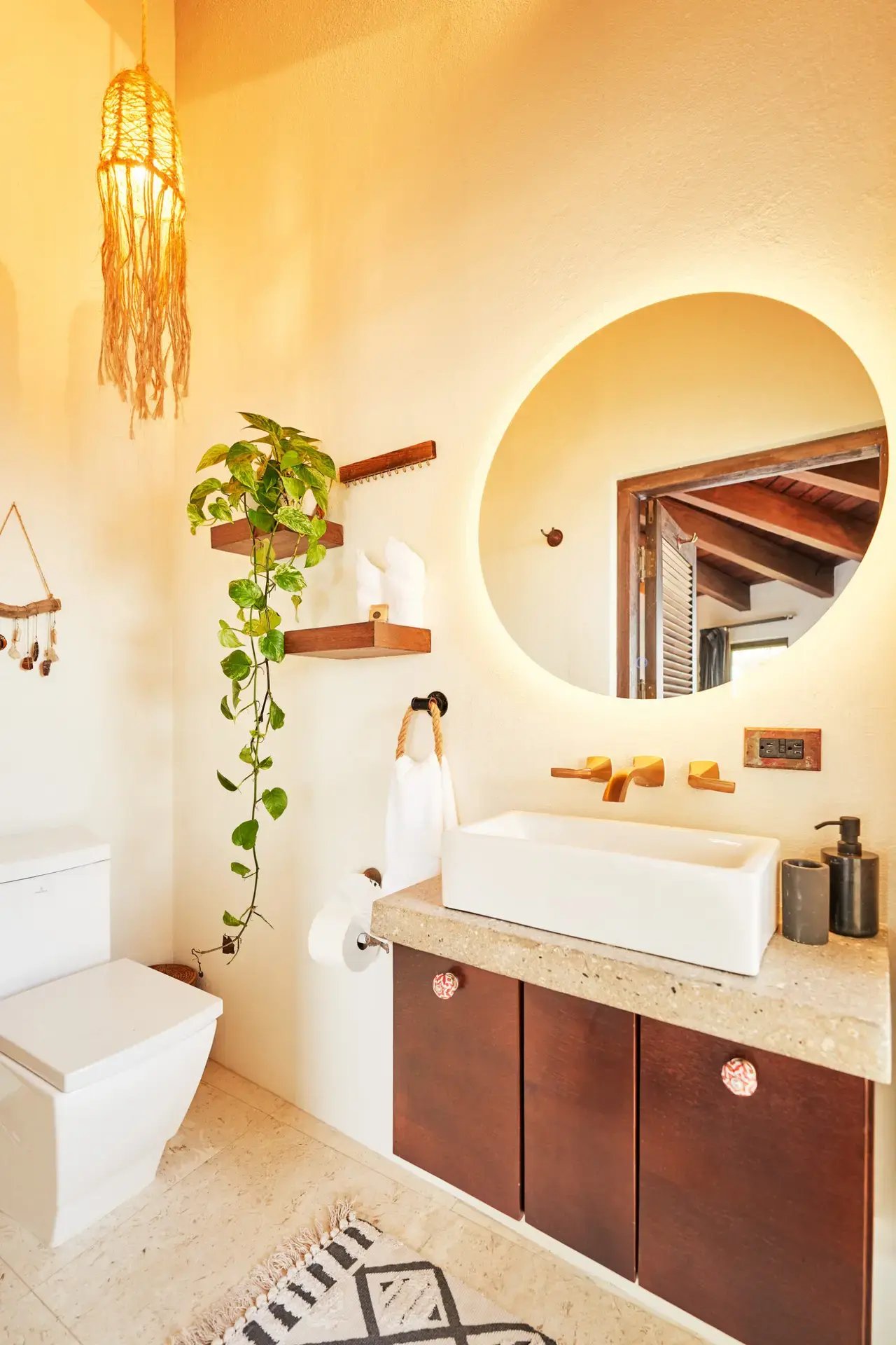 Bathroom vanity with round mirror and hanging macramé light.