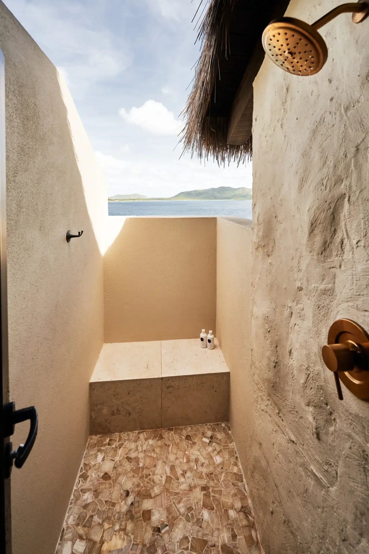 Outdoor shower with stone walls and ocean view.