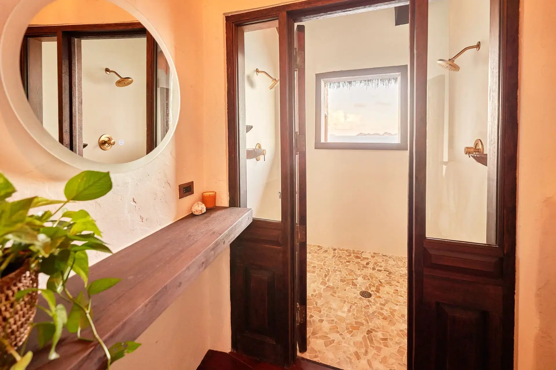 Bathroom with dual glass-door showers and round mirror.
