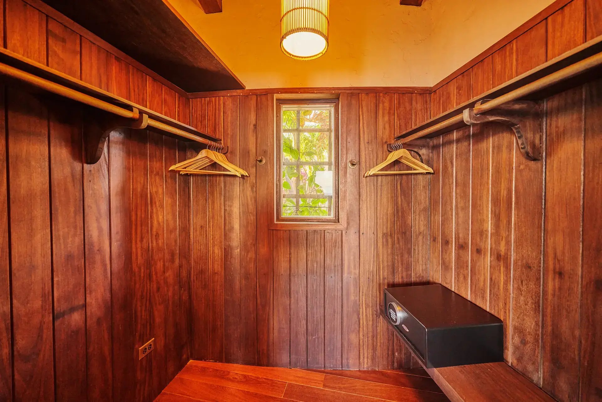 Wood-paneled closet with hanging rods and in-room safe.