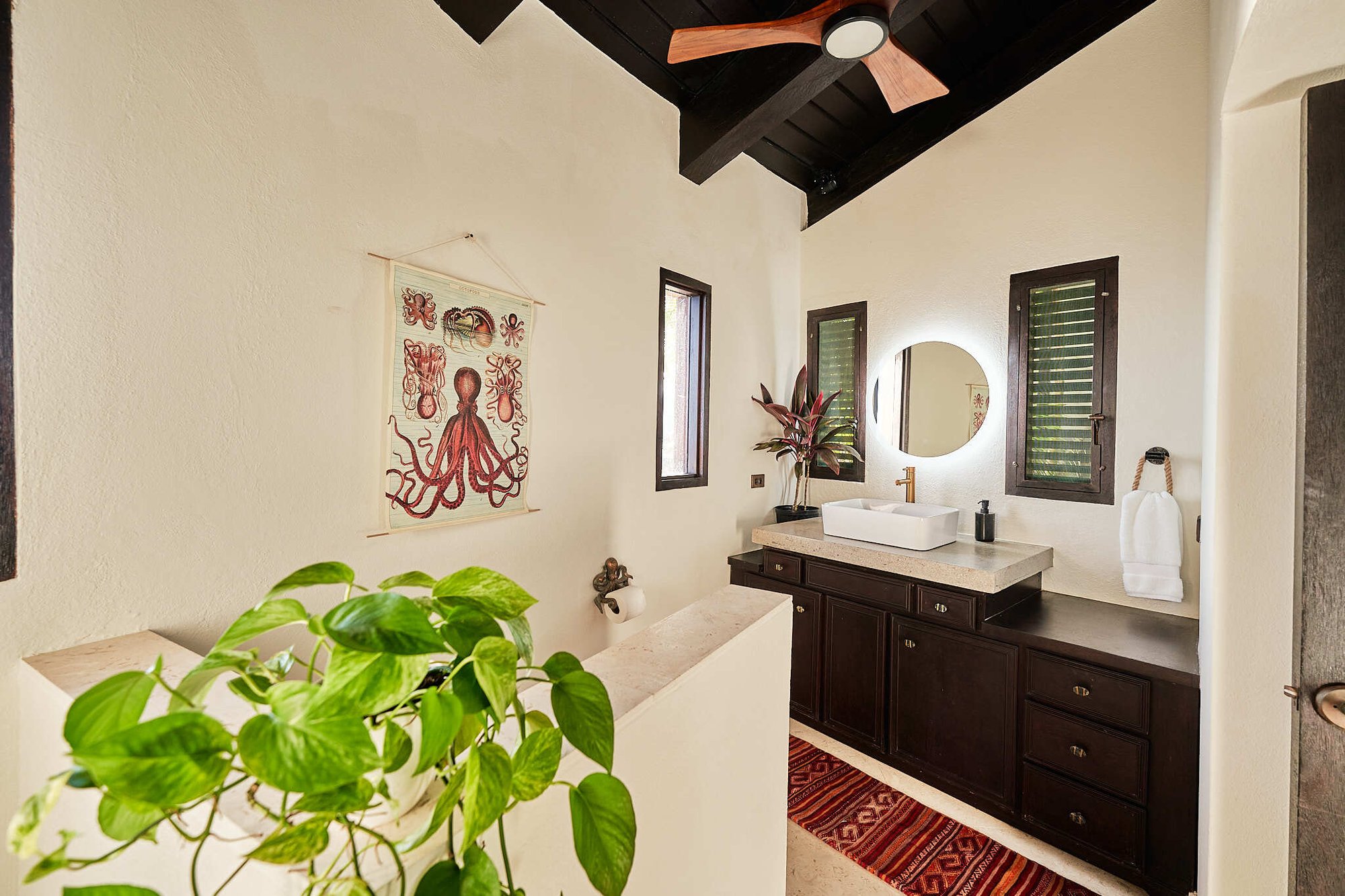 Bathroom with dark wood vanity and octopus wall art.