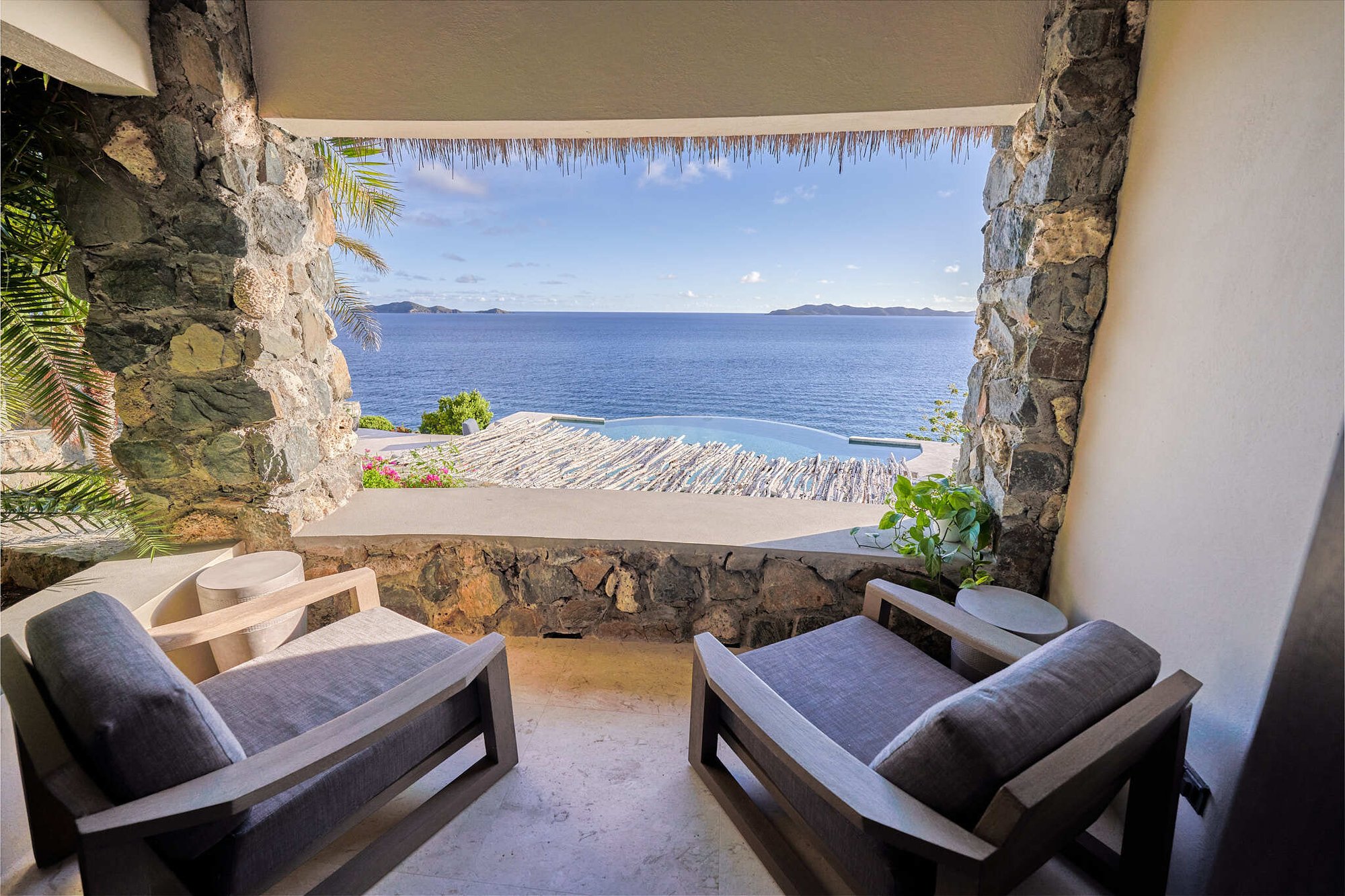 Stone-arch terrace with lounge chairs overlooking infinity pool.