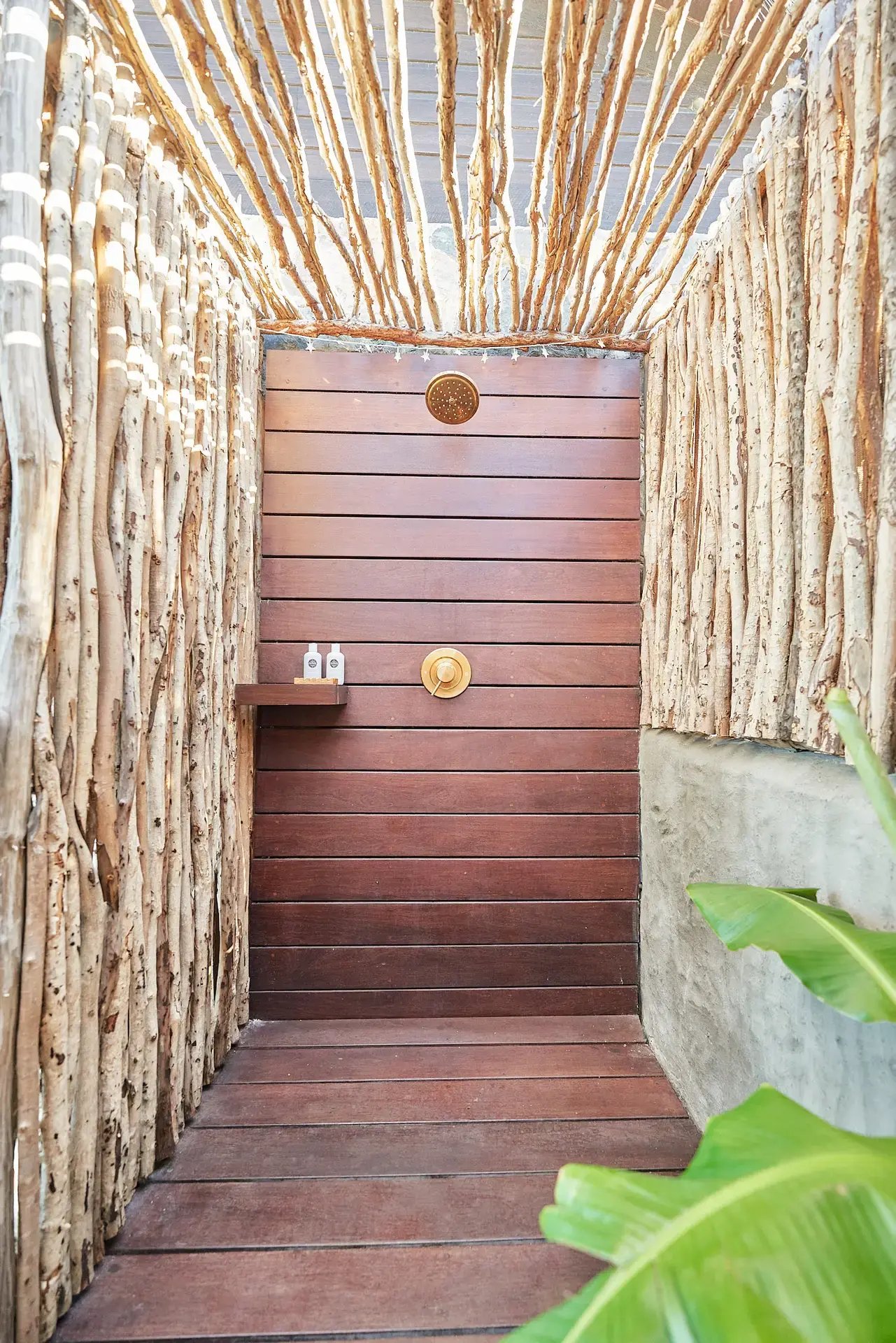 Outdoor shower with driftwood walls and wood-plank flooring.