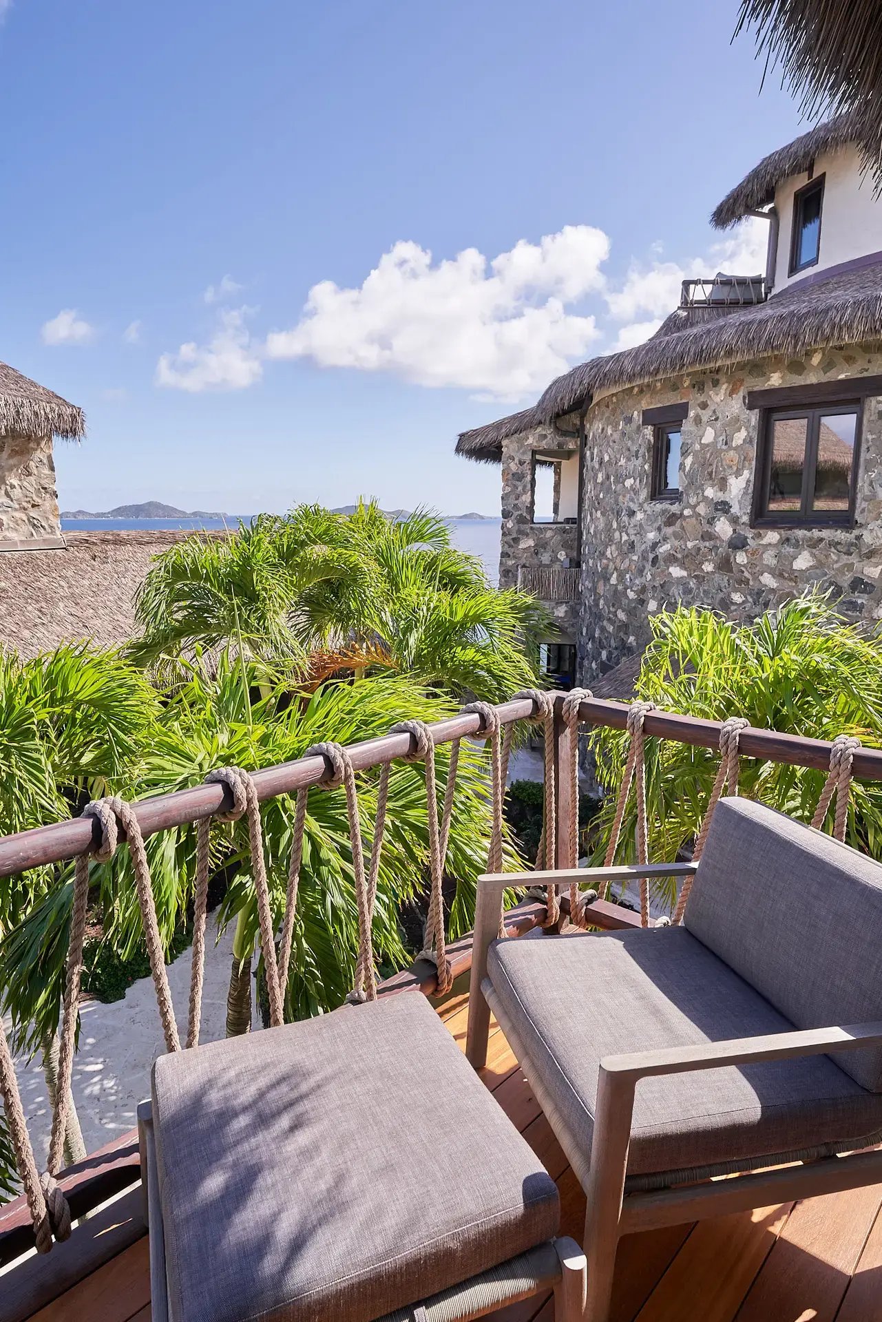Stone villa exterior with palm trees and ocean view.