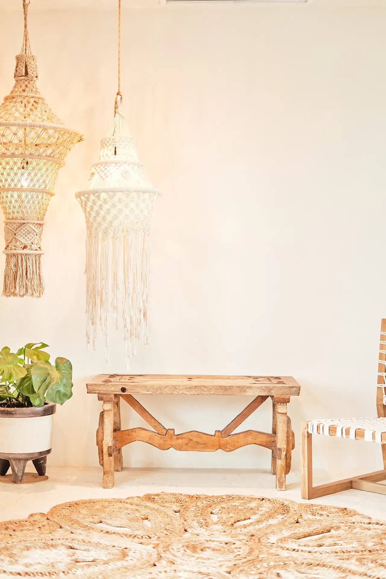Entryway with macramé pendant lights and wooden bench.