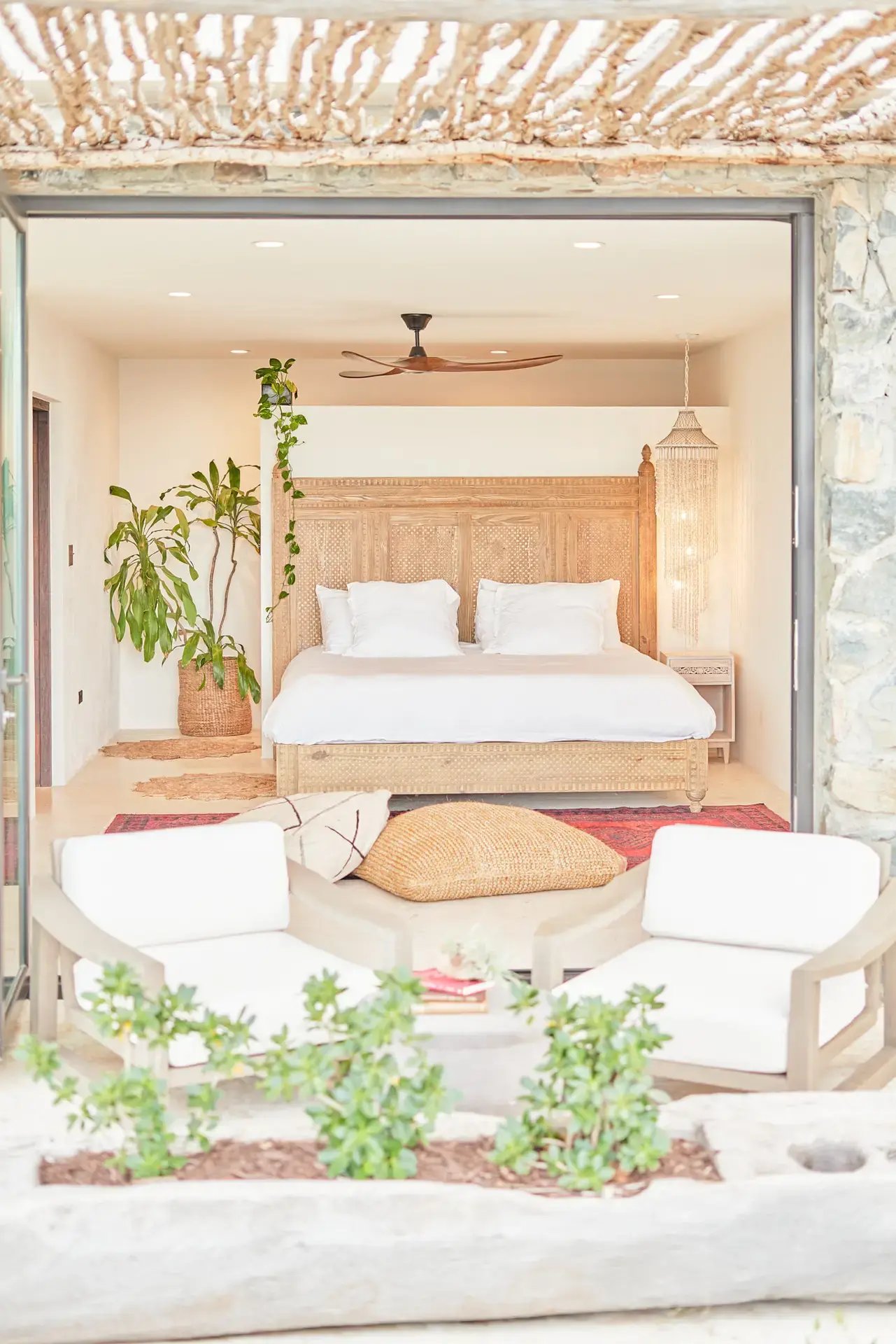 Bedroom opening onto a terrace with lounge seating and greenery.