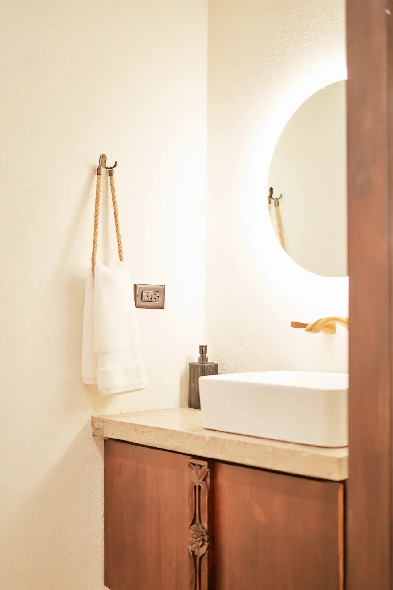 Bathroom vanity with round mirror and wood cabinetry.