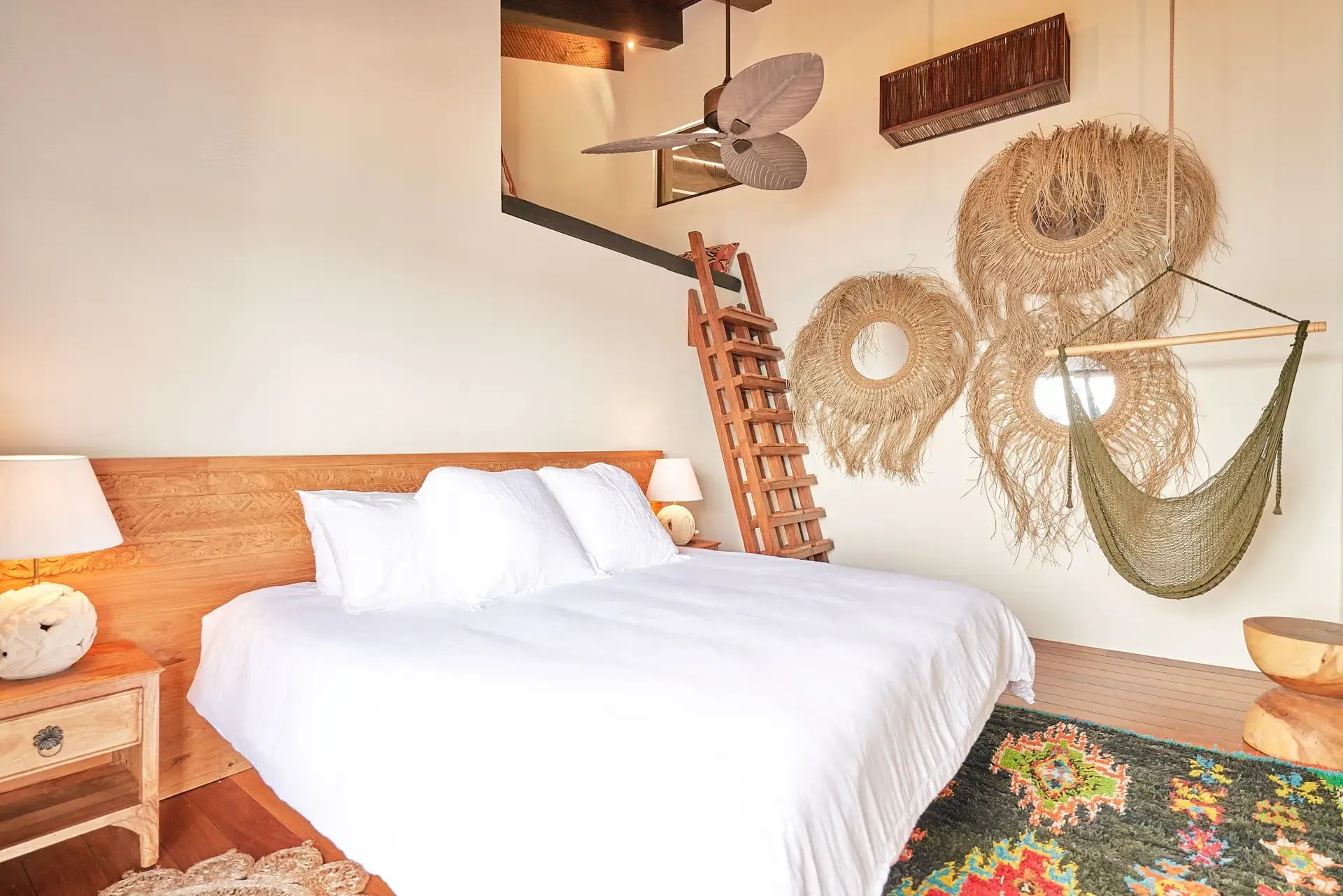 Bedroom with woven wall hangings, ladder, and hanging hammock chair.