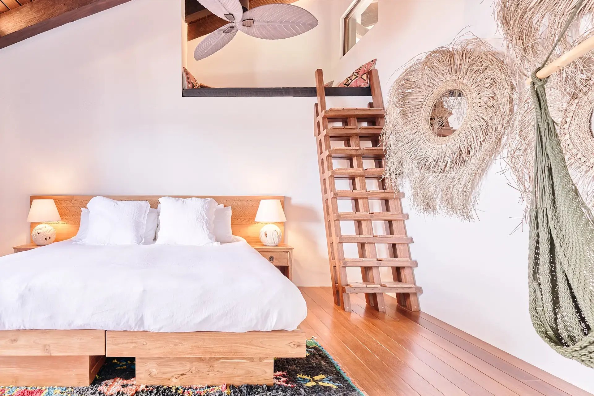 Bedroom with carved headboard, ladder, and hanging fiber decor.