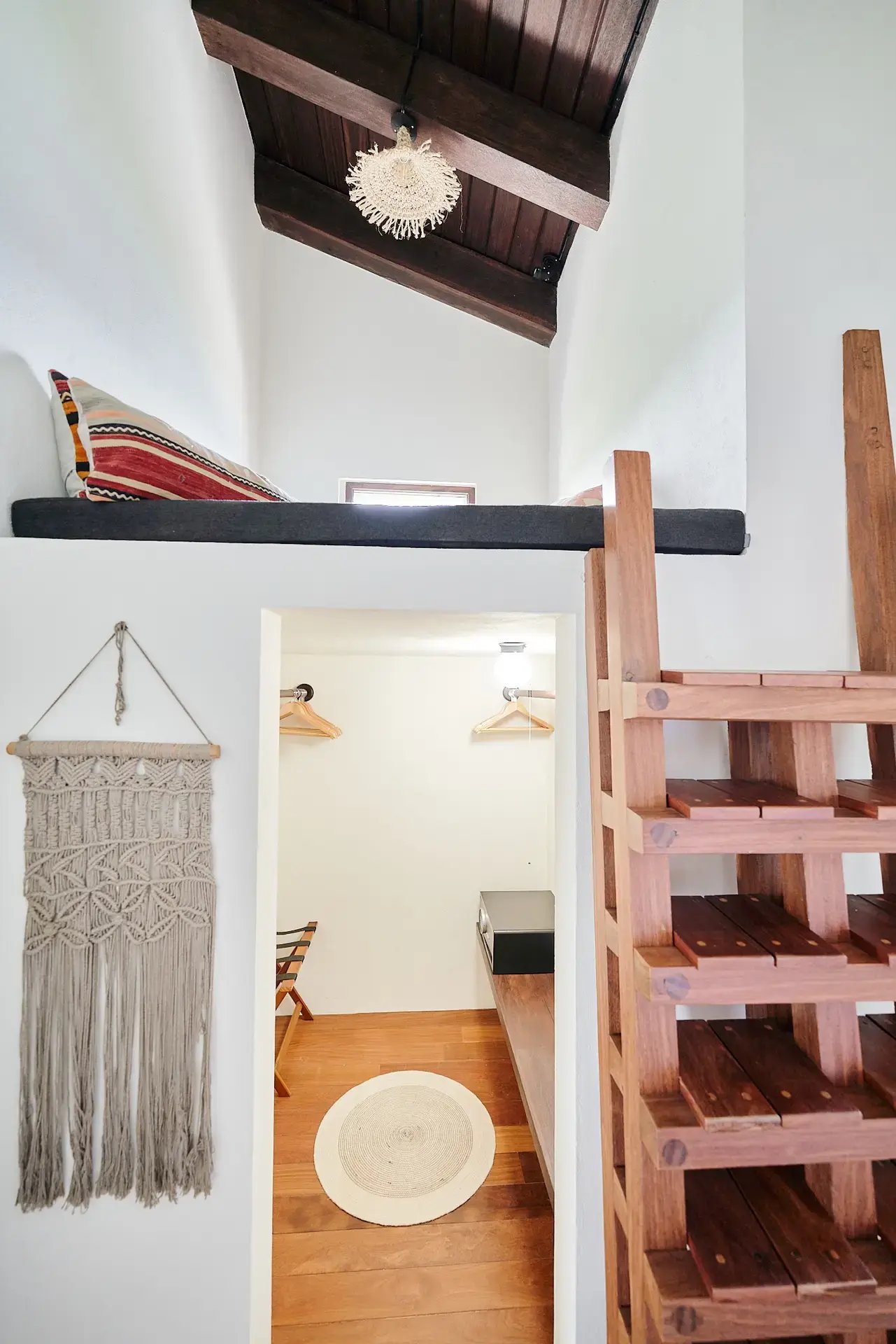 Loft nook with macramé decor overlooking a wood-paneled closet.