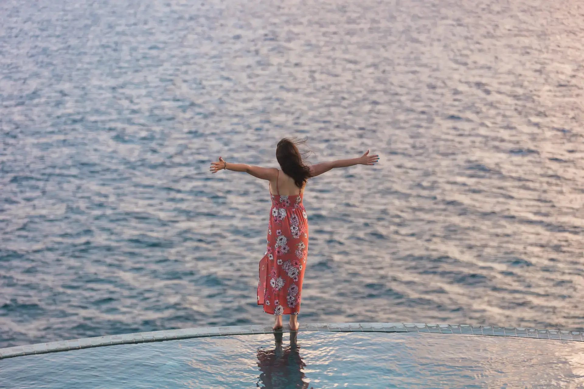 Guest standing with arms outstretched at the edge of the infinity pool at The Aerial, BVI