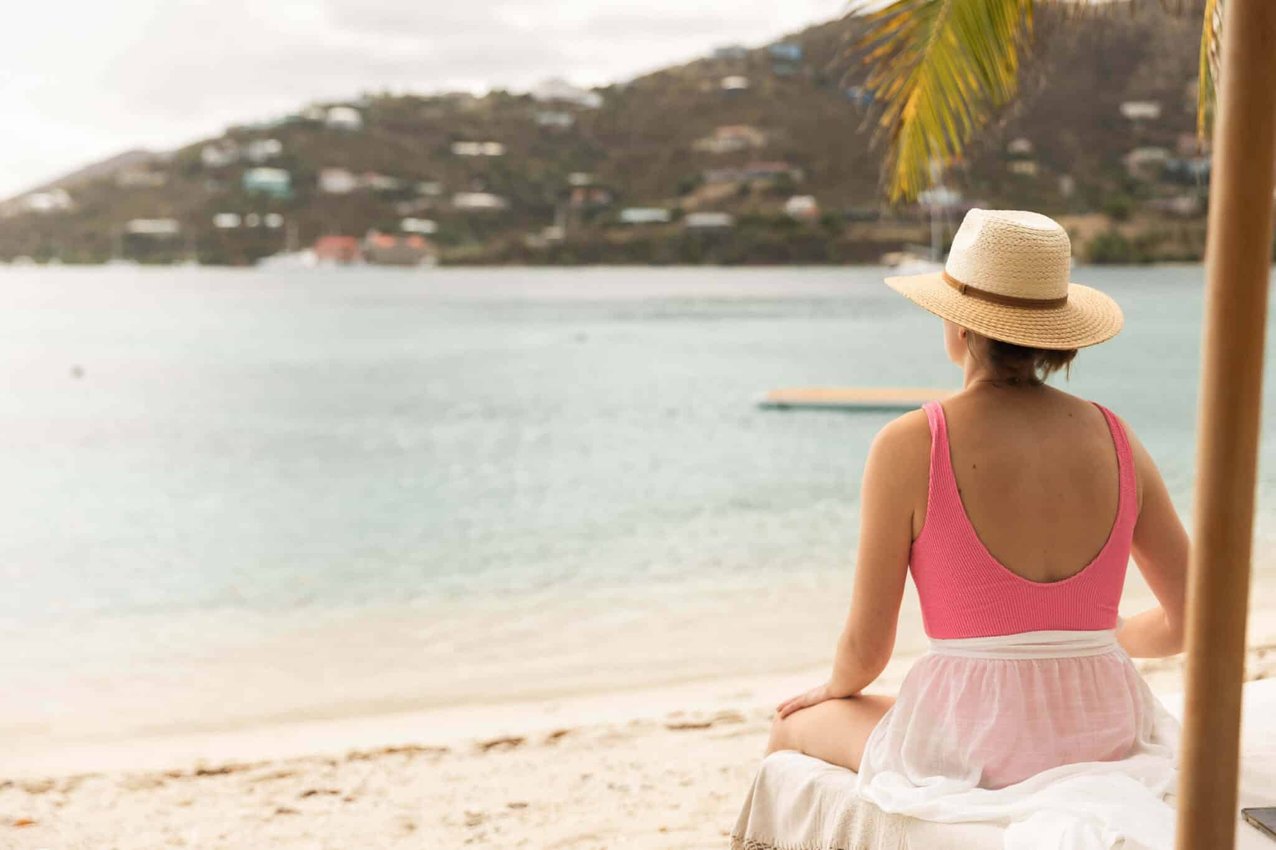 Guest sitting quietly on the beach facing the ocean at The Aerial, BVI