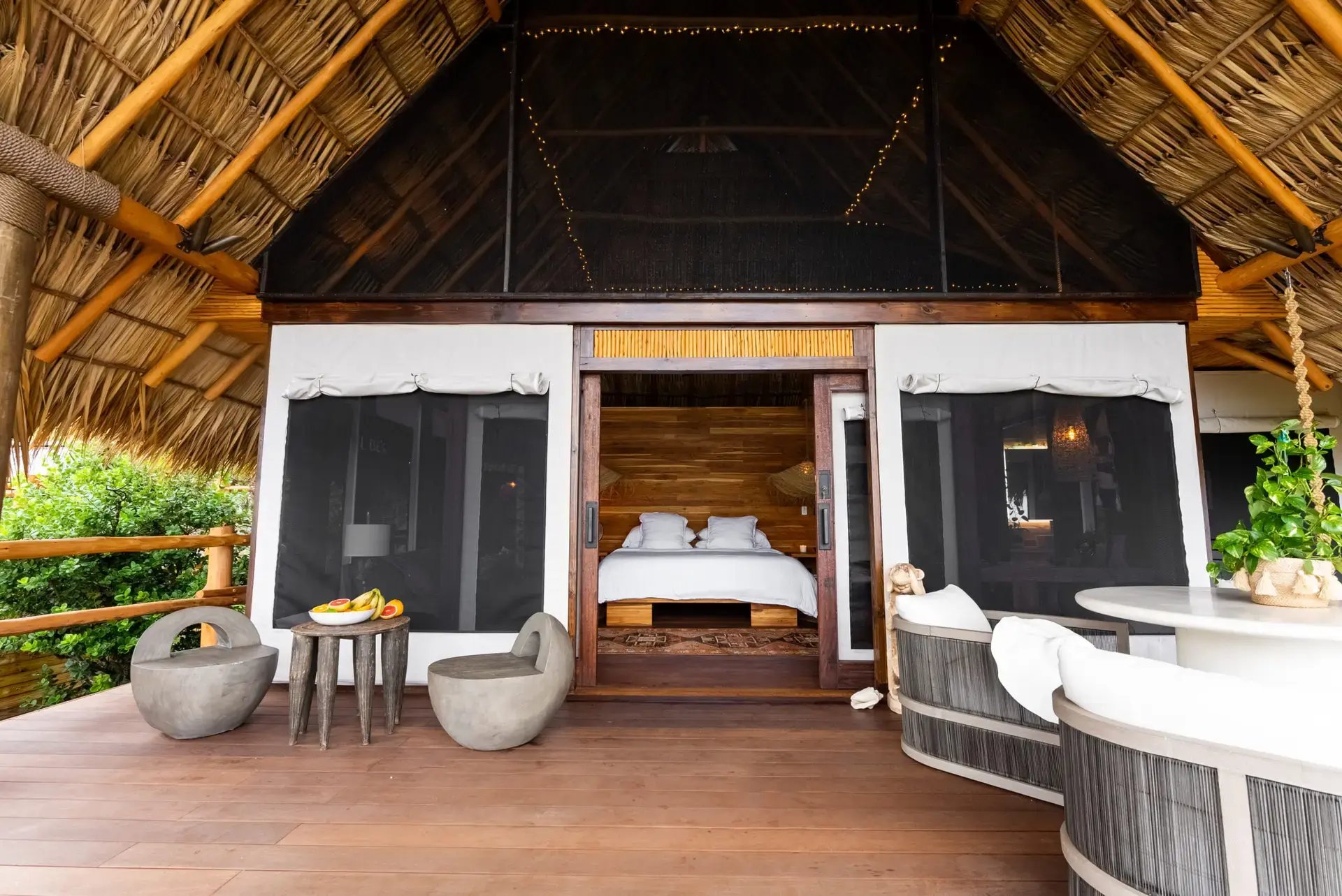 Deck with stone stools leading into a thatched-roof bedroom.