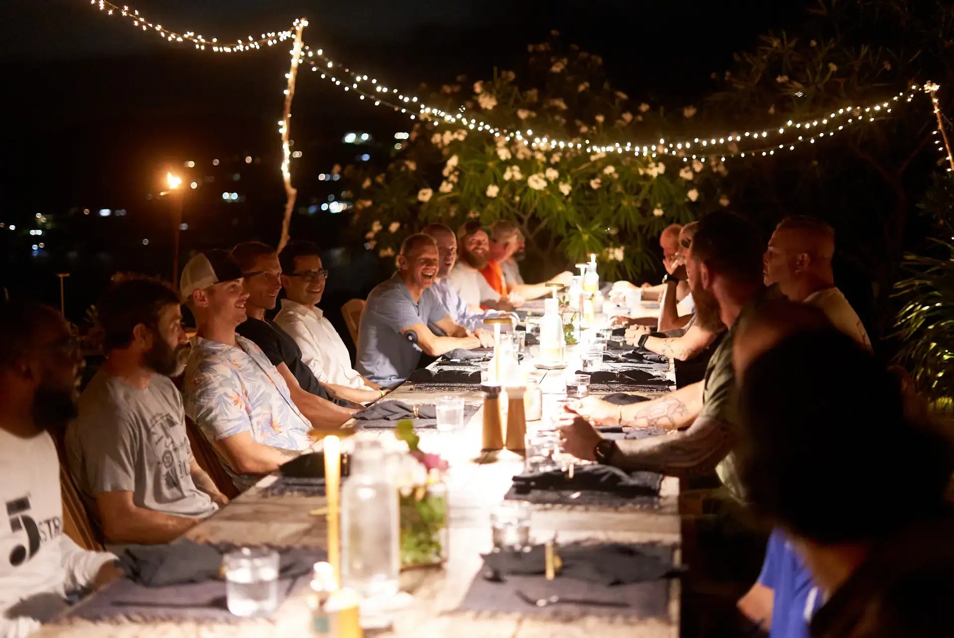 Guests dining together at a long outdoor table at night at The Aerial BVI