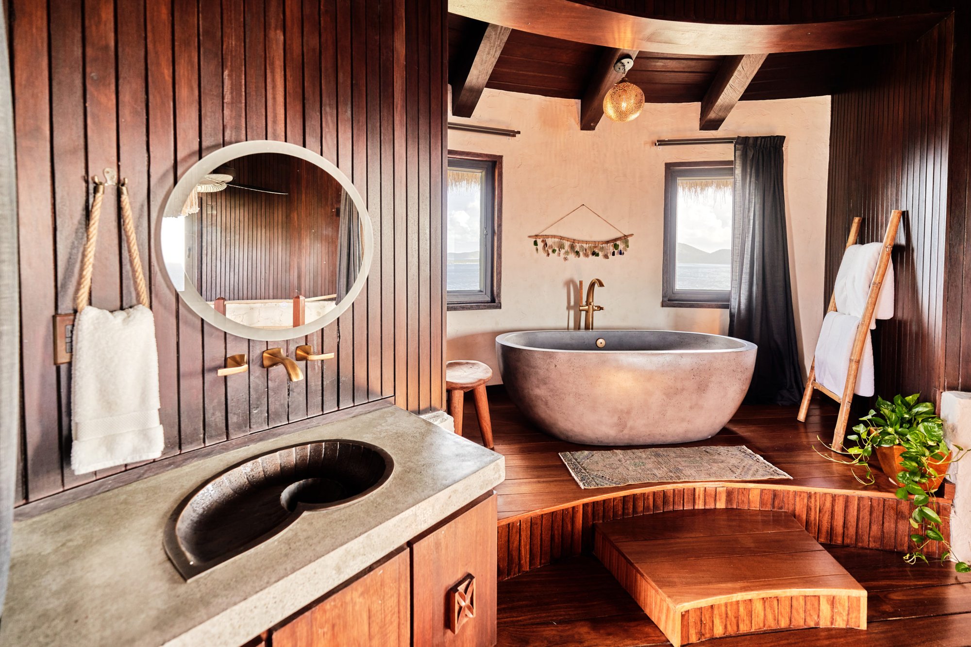 Bathroom with a freestanding stone tub and round mirror at The Aerial, BVI