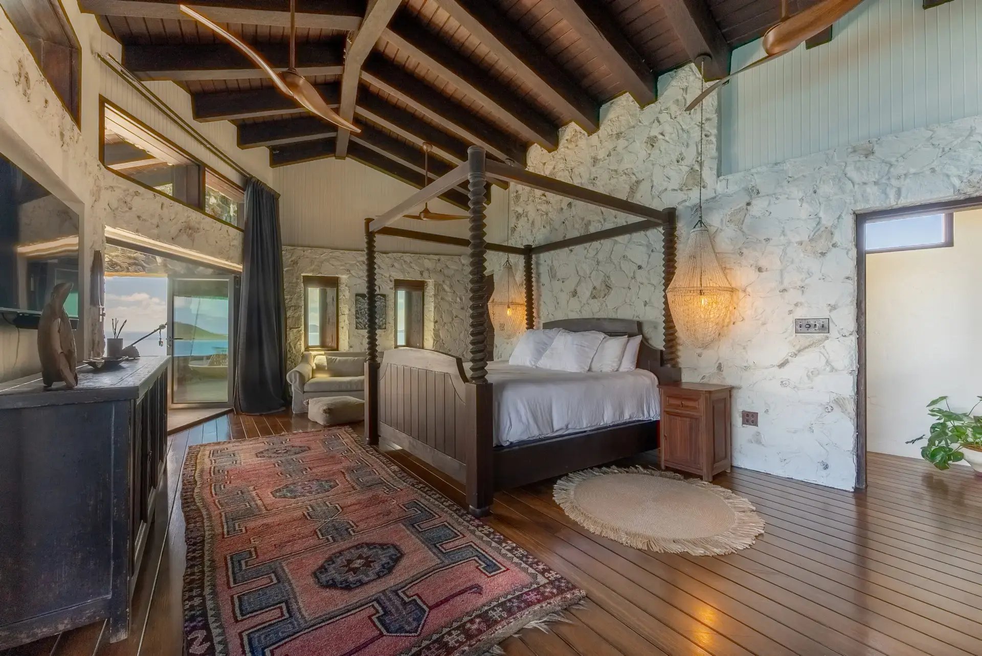 Four-poster bed with stone wall backdrop at The Aerial, BVI