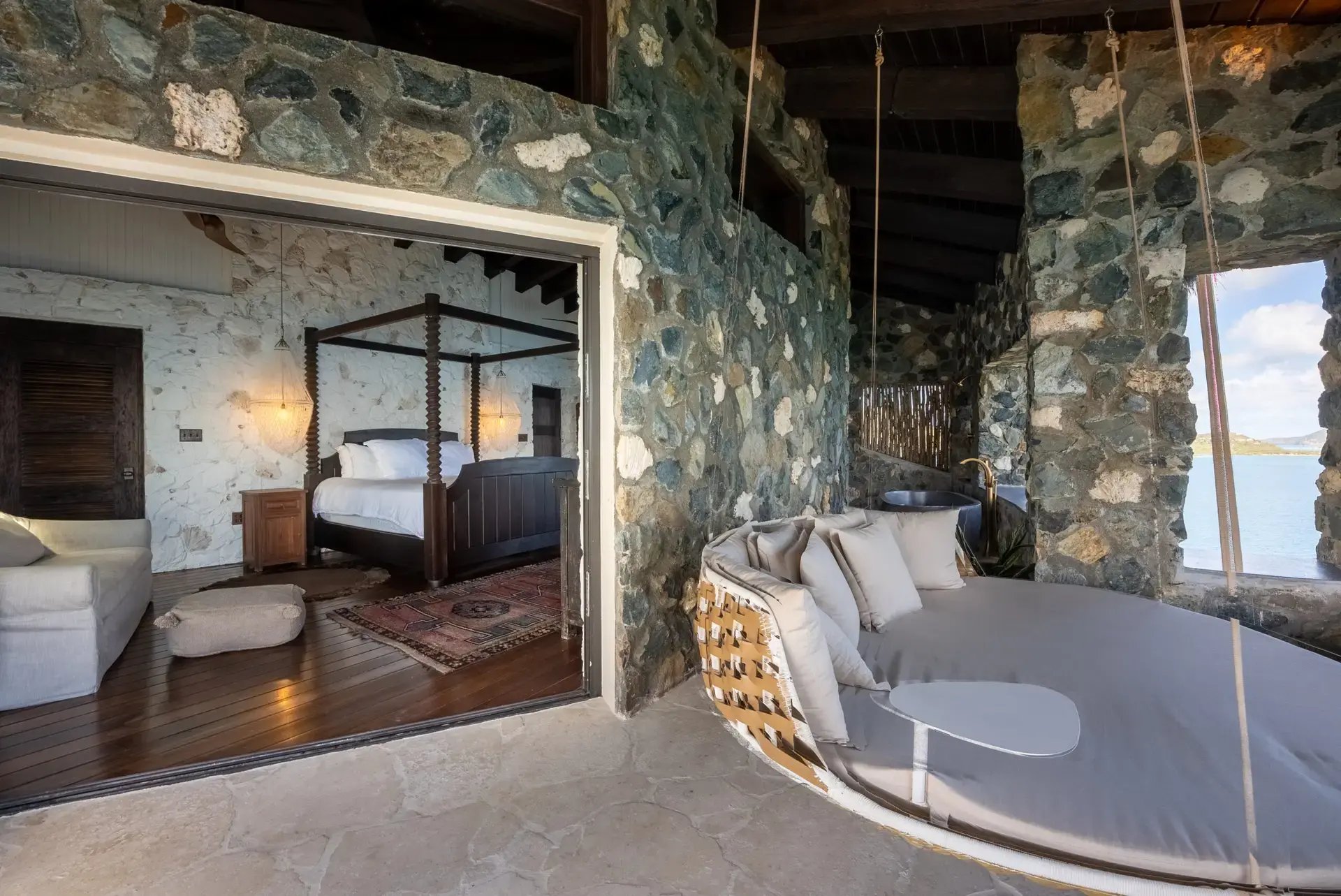 Bedroom opening to a stone-walled outdoor lounge at The Aerial, BVI