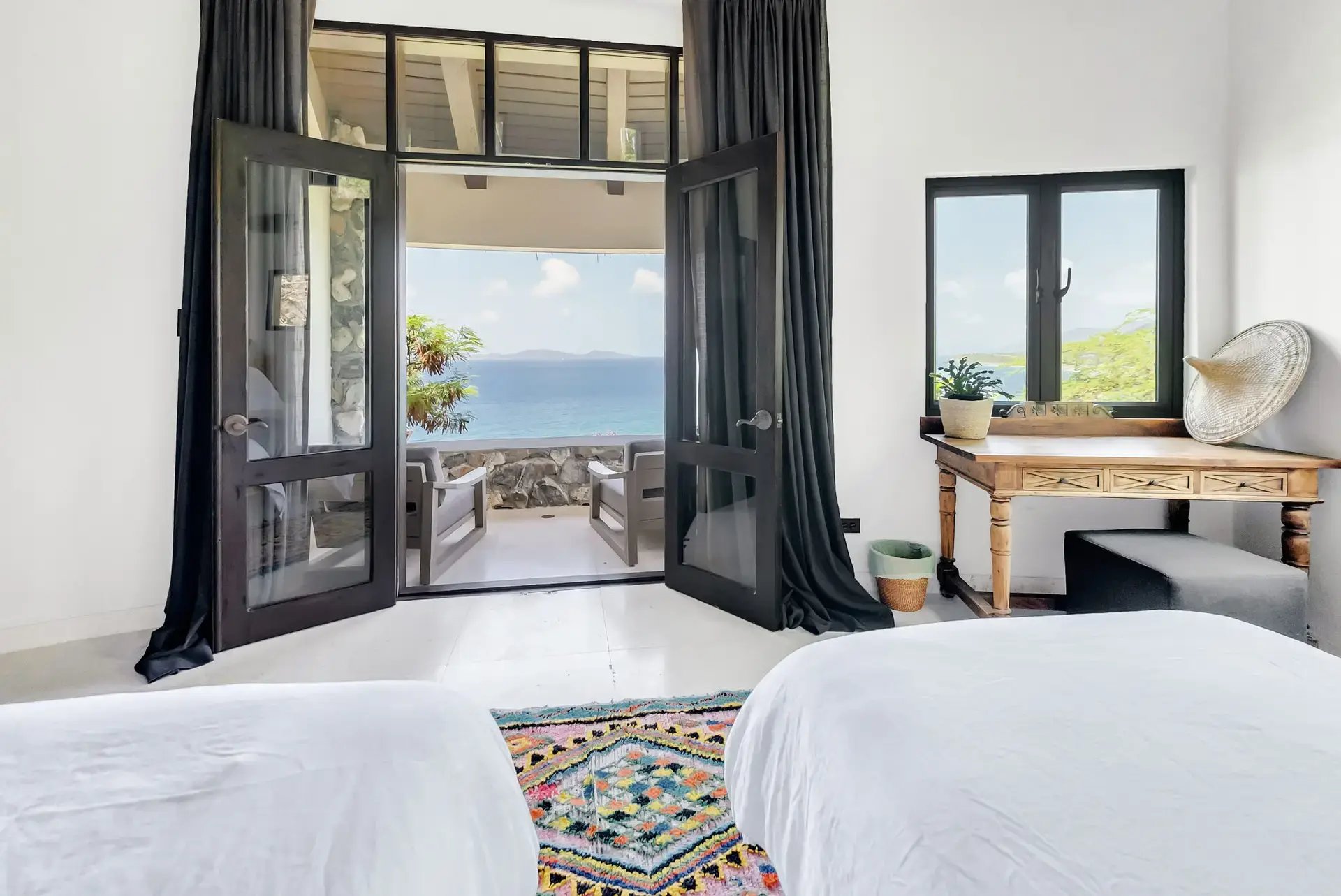 Twin beds facing glass doors opening to ocean-view balcony.