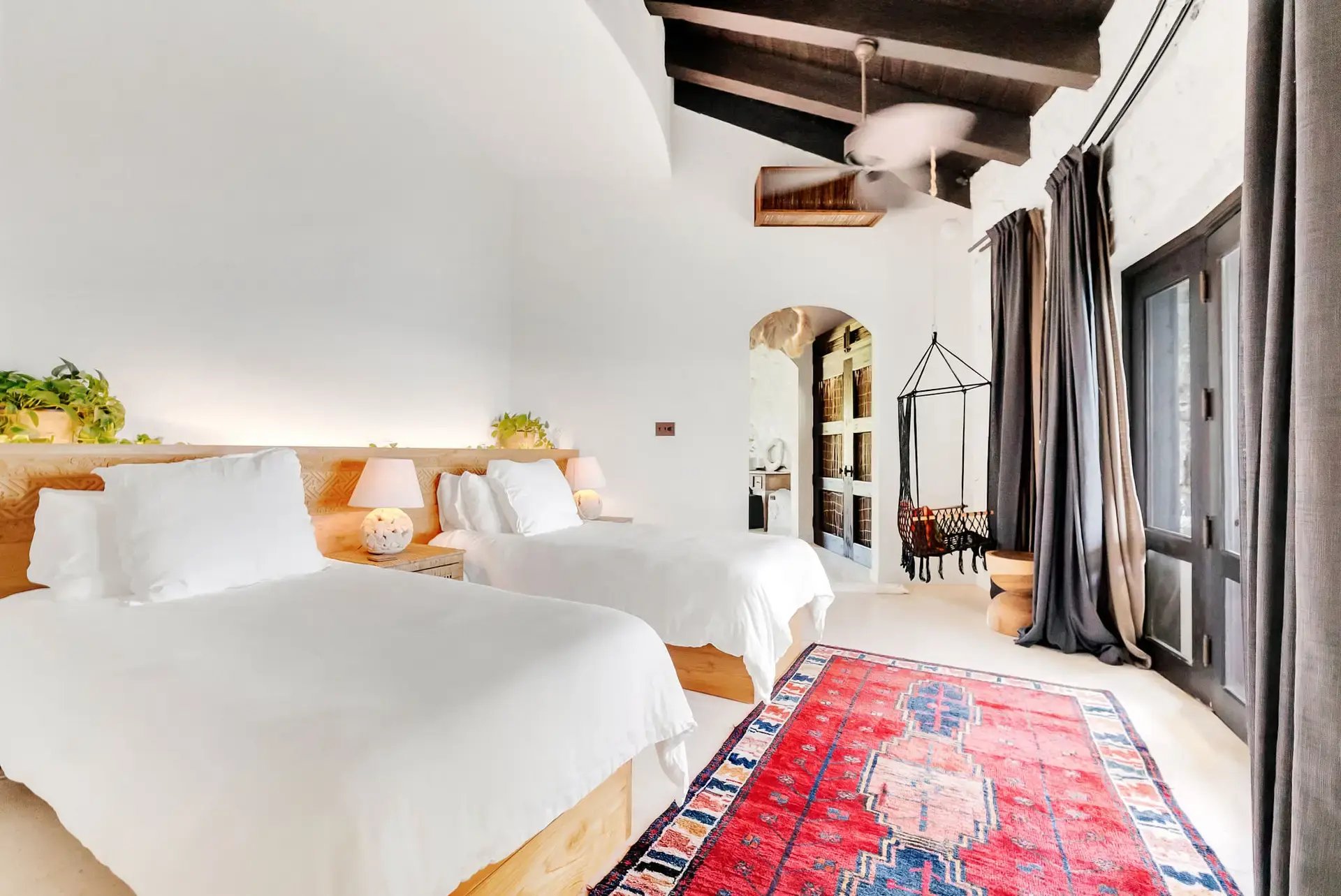 Twin beds with hanging chair and stone archway at The Aerial, BVI