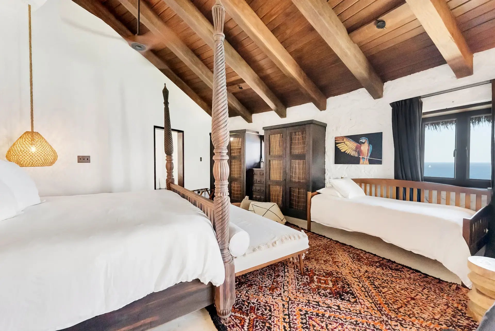 Twin four-poster beds with parrot artwork at The Aerial, BVI