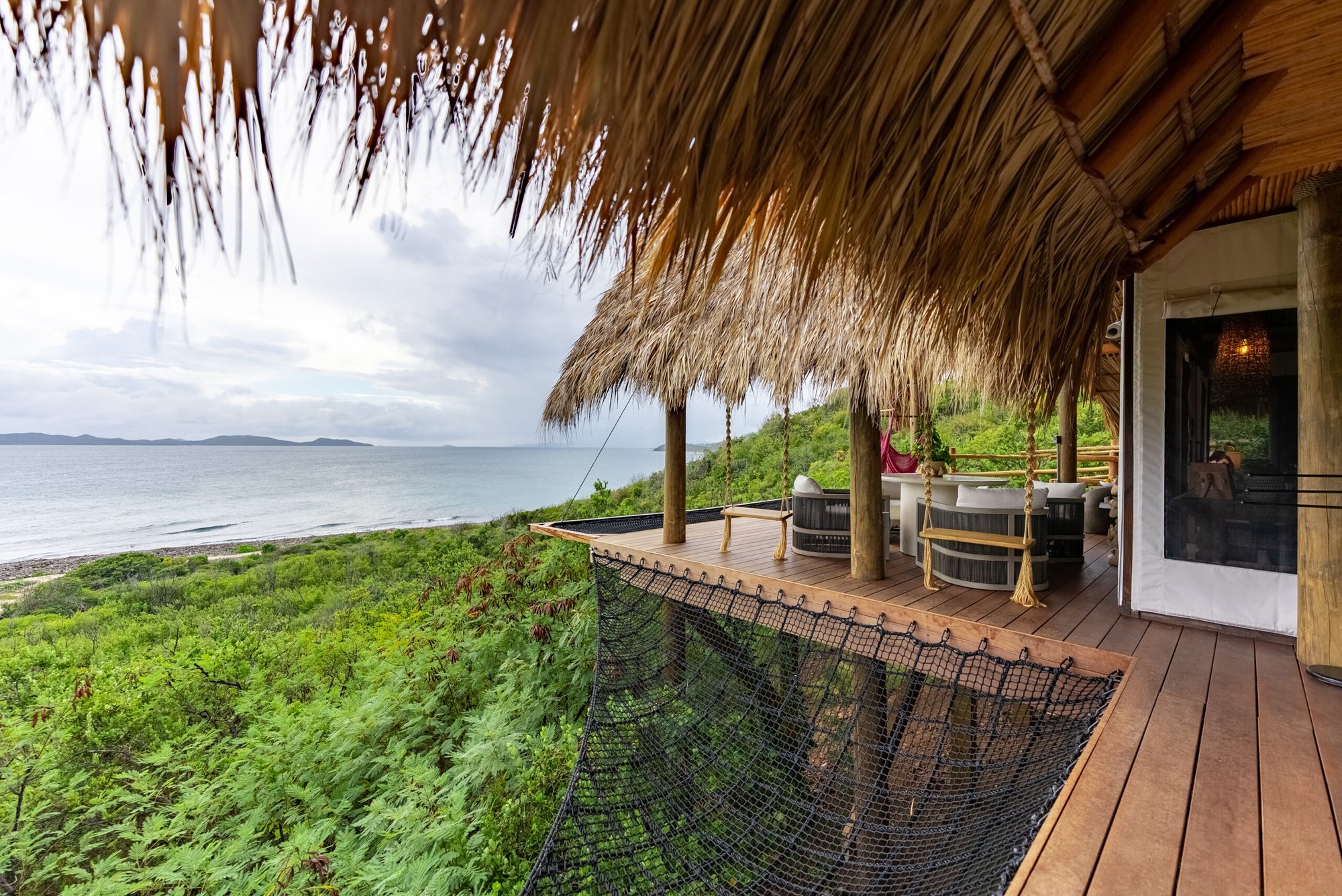 Elevated wood deck overlooking the coastline through palm trees.