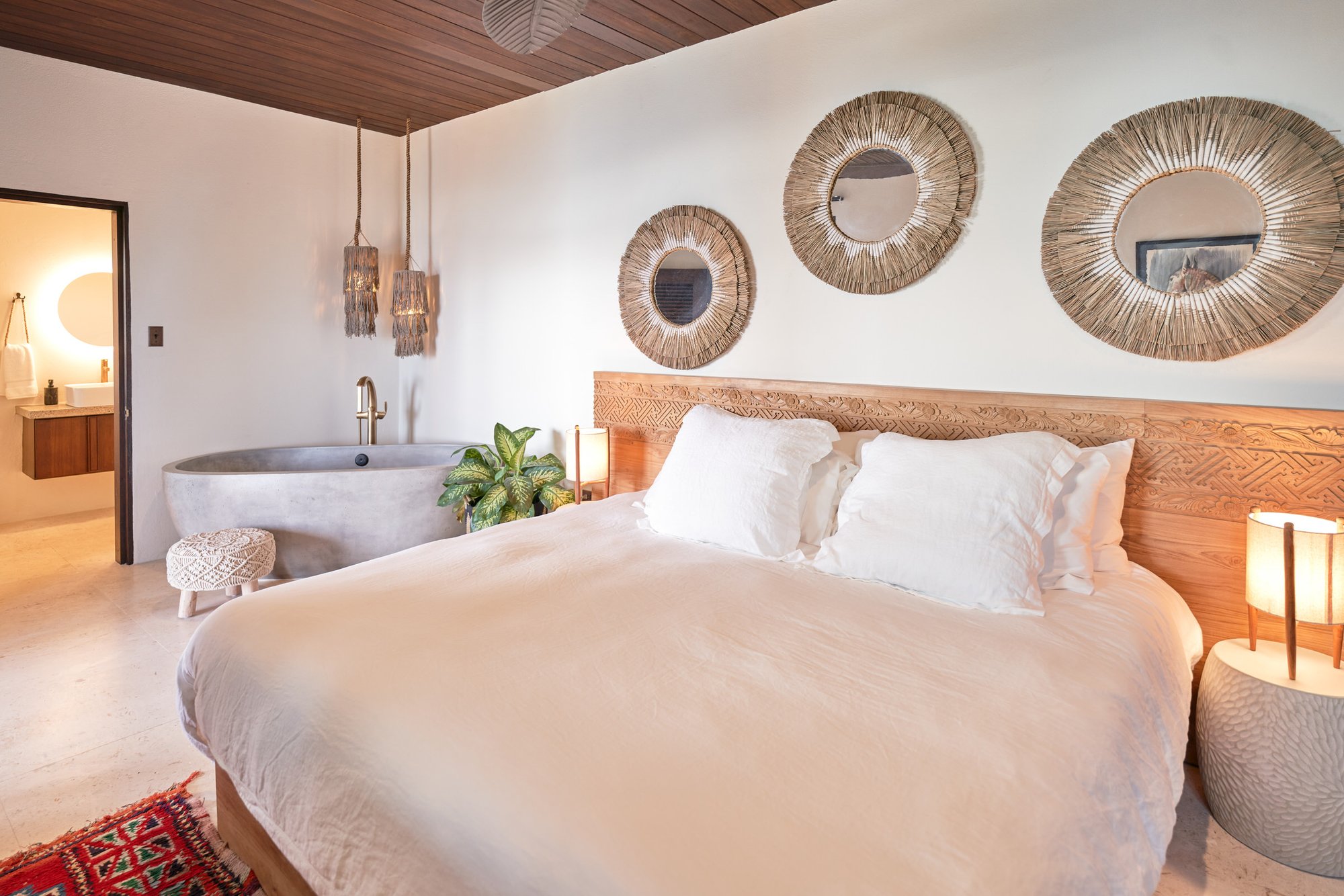 King bed with sunburst mirrors and ocean-view bathtub at The Aerial, BVI