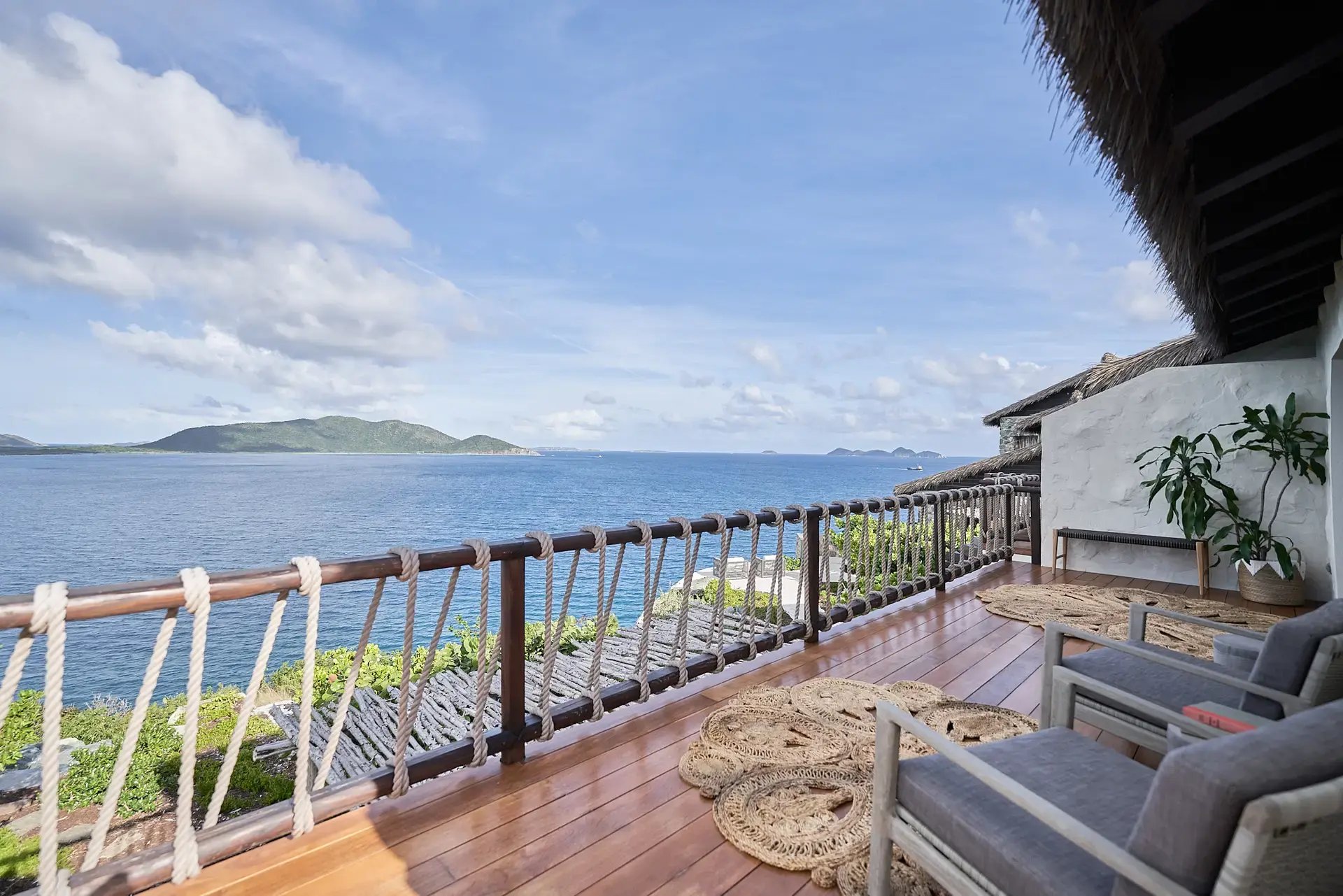 Oceanview deck with lounge seating and thatched roof overhang.