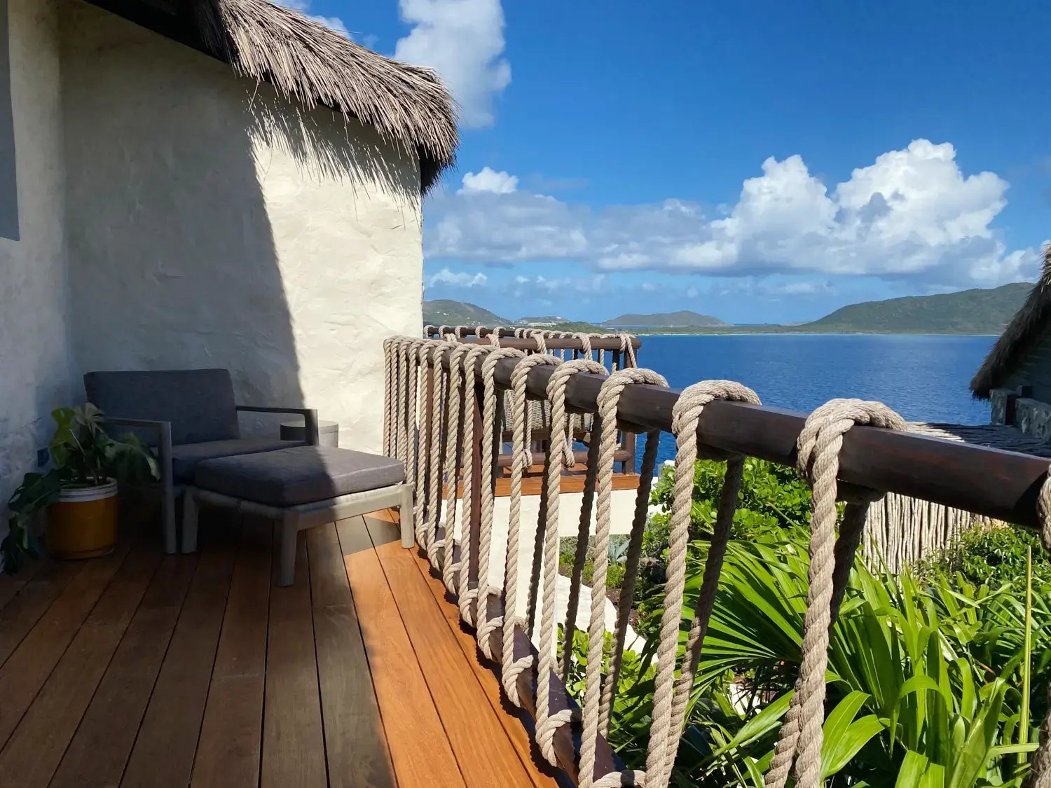 Oceanview terrace with rope railing and lounge chair.