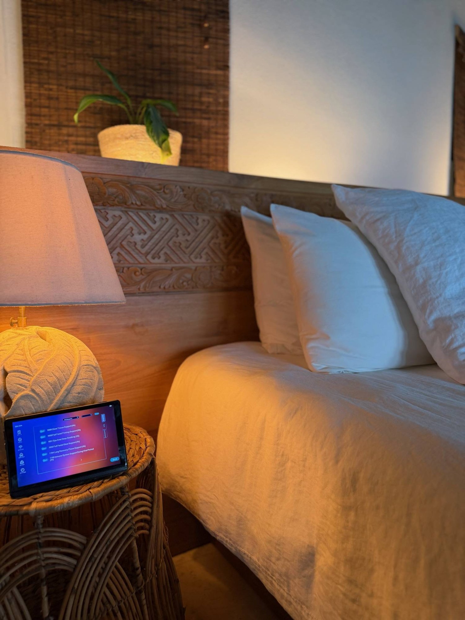 Zen Vein device on bedside table beside a carved wooden headboard.