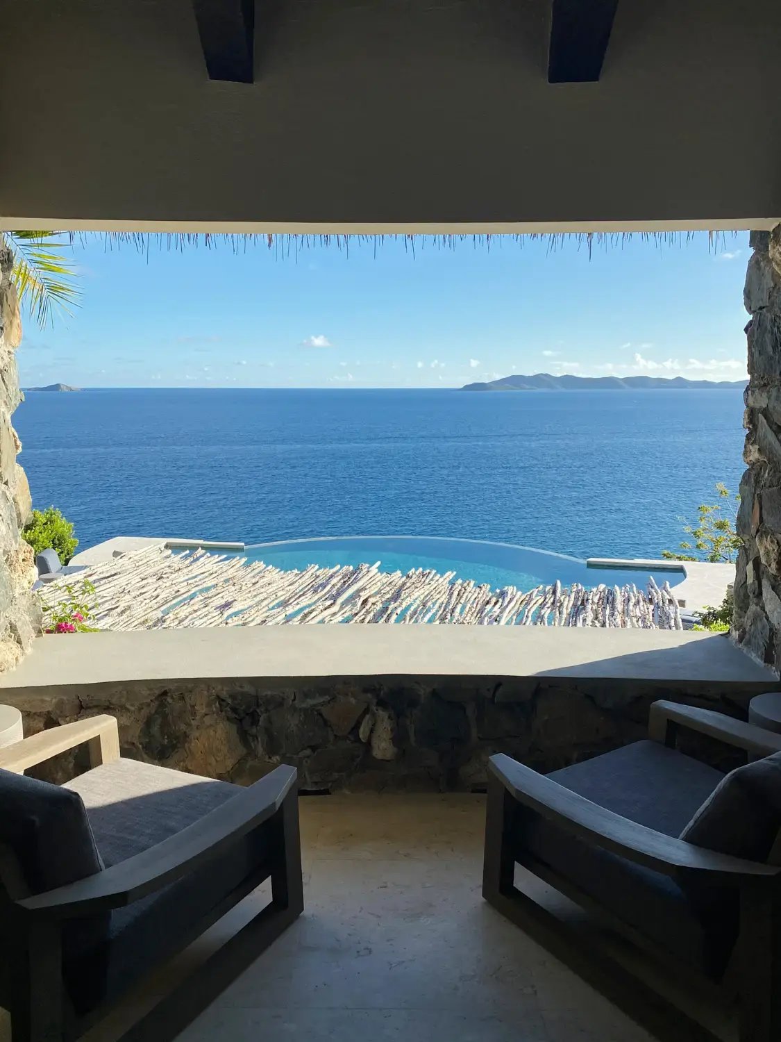 Stone archway framing an infinity pool and ocean view.