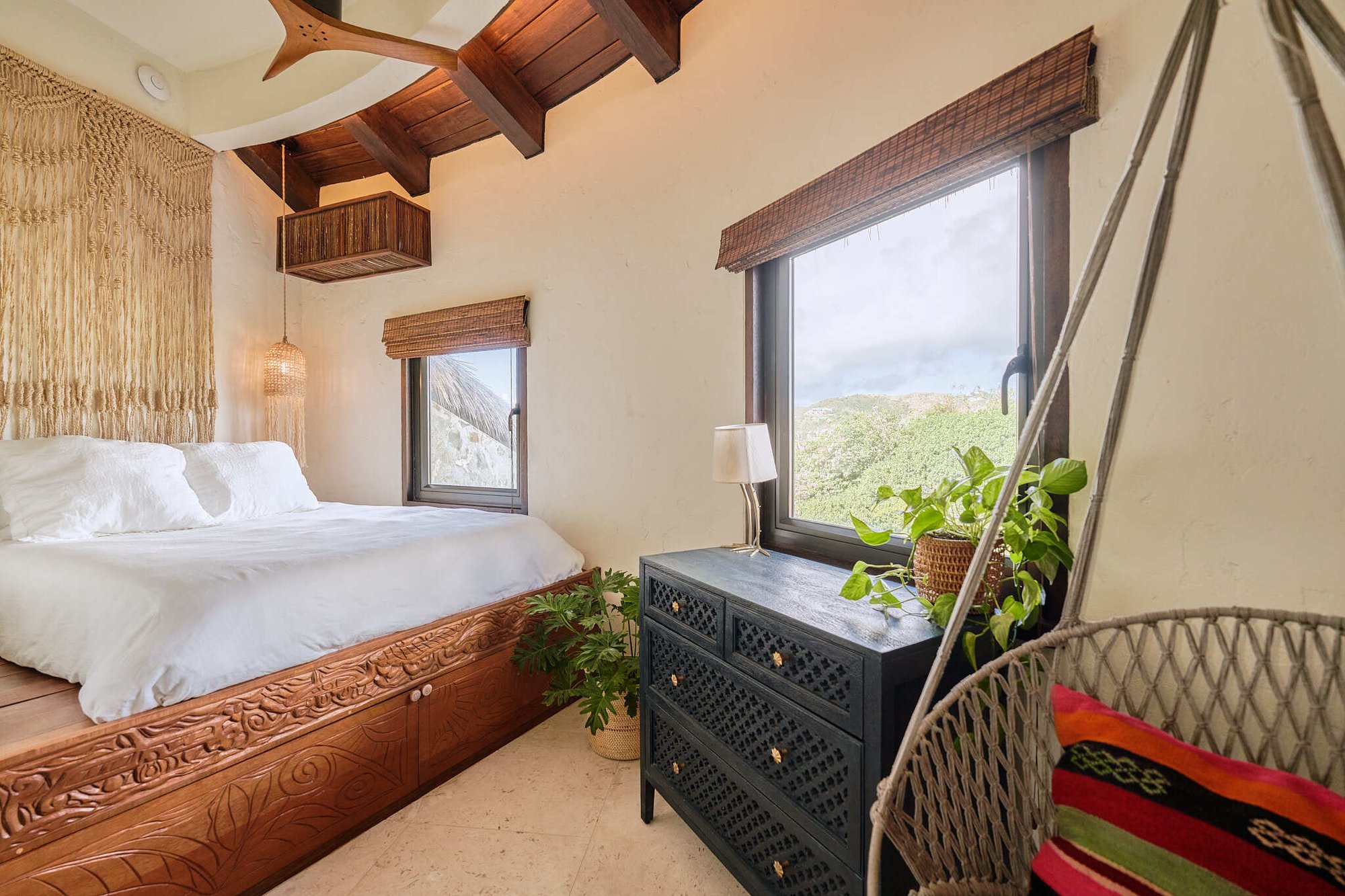 King bed with macrame headboard and hanging chair at The Aerial, BVI