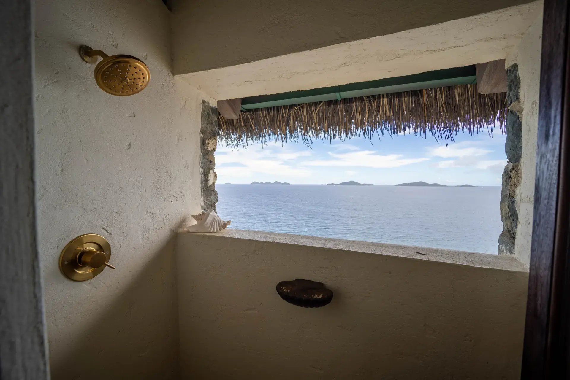 Outdoor shower with ocean view through a stone wall opening at The Aerial, BVI