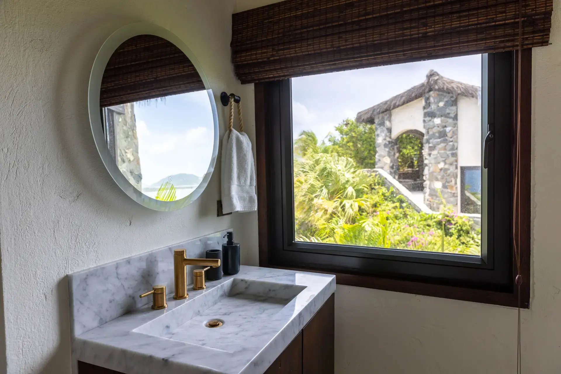 Bathroom vanity with round mirror overlooking stone architecture at The Aerial, BVI