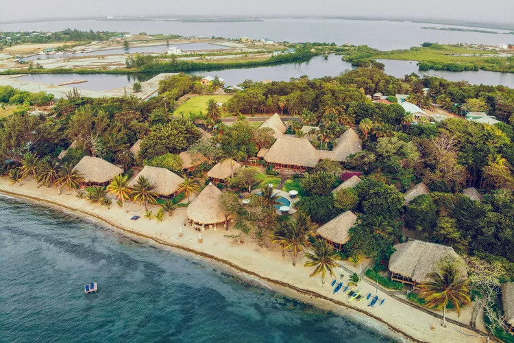 Aerial view of a thatched-roof resort village along the coastline