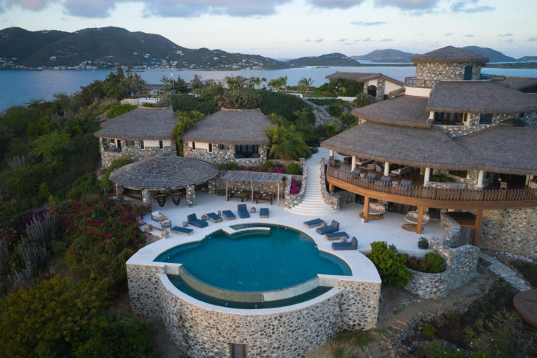 Aerial view of a hillside resort with an infinity pool in the BVI