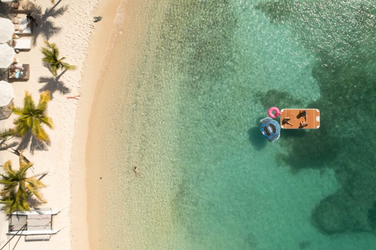 Aerial view of a beach with a floating dock in turquoise water