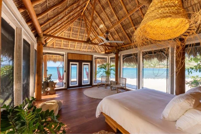 Guest room interior with ocean-view doors and a thatched roof